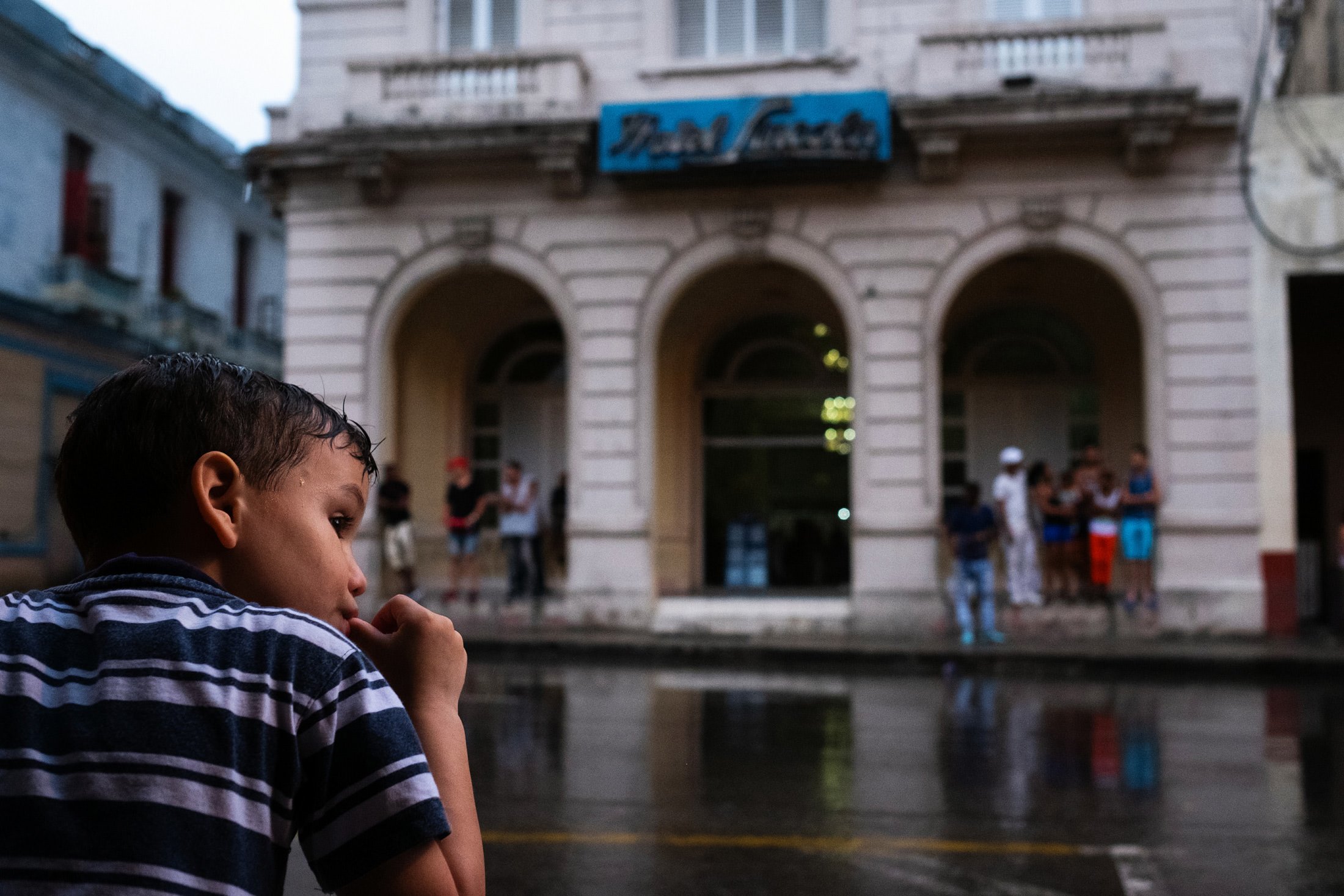 young boy sucking his thumb in the rain in Havana, Cuba