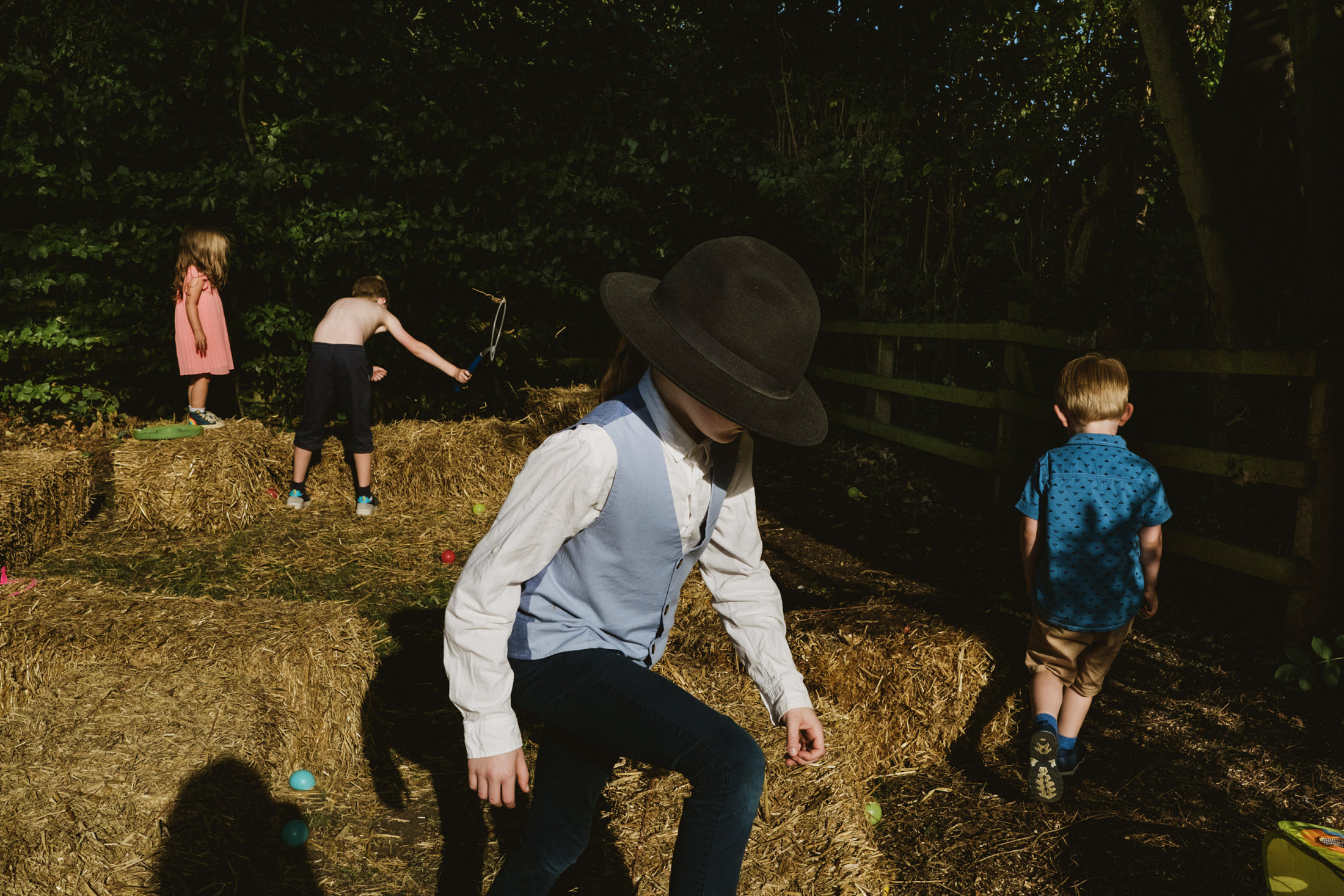 Children playing on hay bales outdoors.
