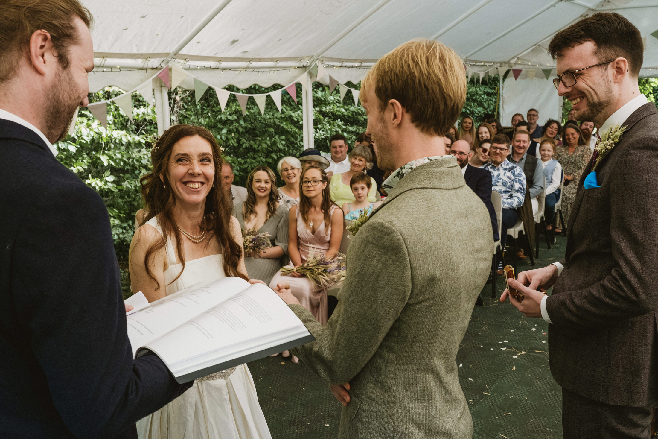 Outdoor wedding ceremony with smiling bride and guests.