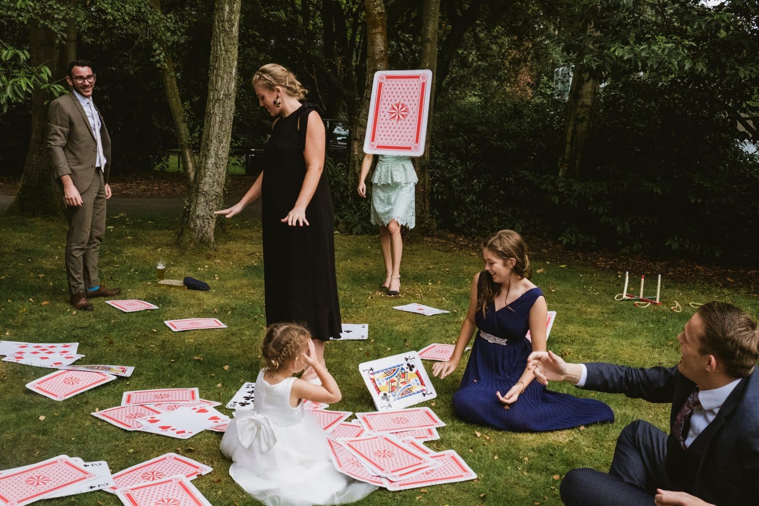 Documentary wedding photographer captures giant playing card mid-flight, perfectly hiding the head and shoulders of a lady in a bridesmaid dress