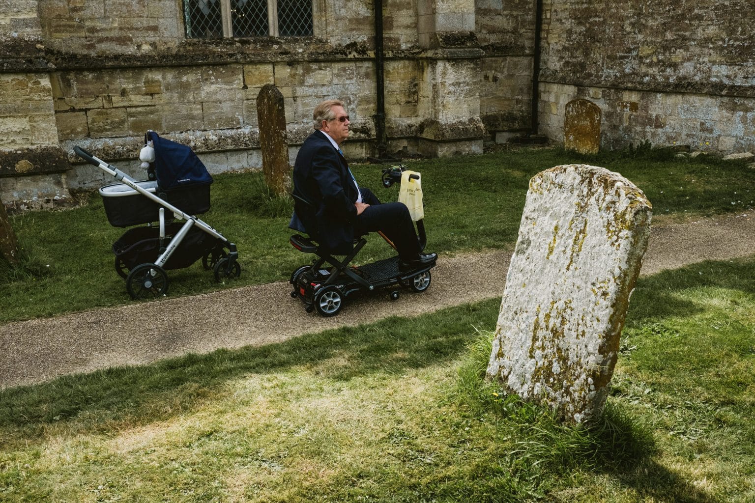 Street Photographers capture a wedding scene. A pram, a man in a mobility scooter and a gravestone signify the "journey of life"