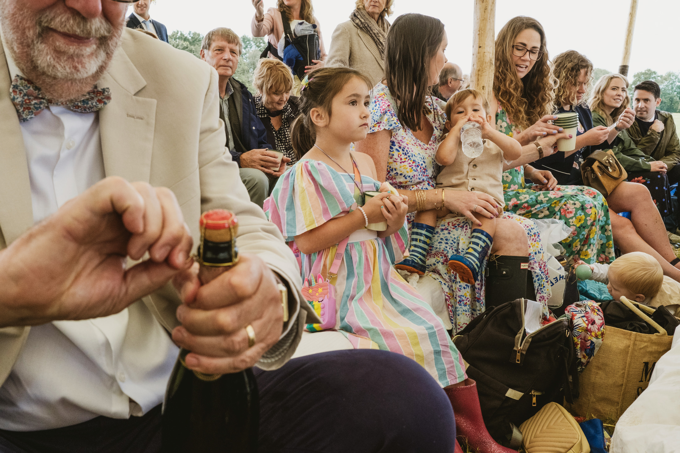 People seated outdoors with drinks and colourful outfits.