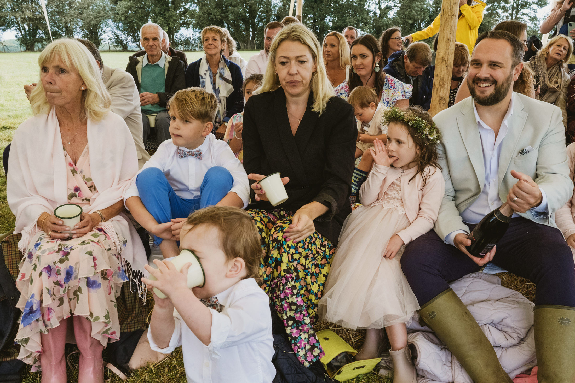 Outdoor gathering with adults and children seated.