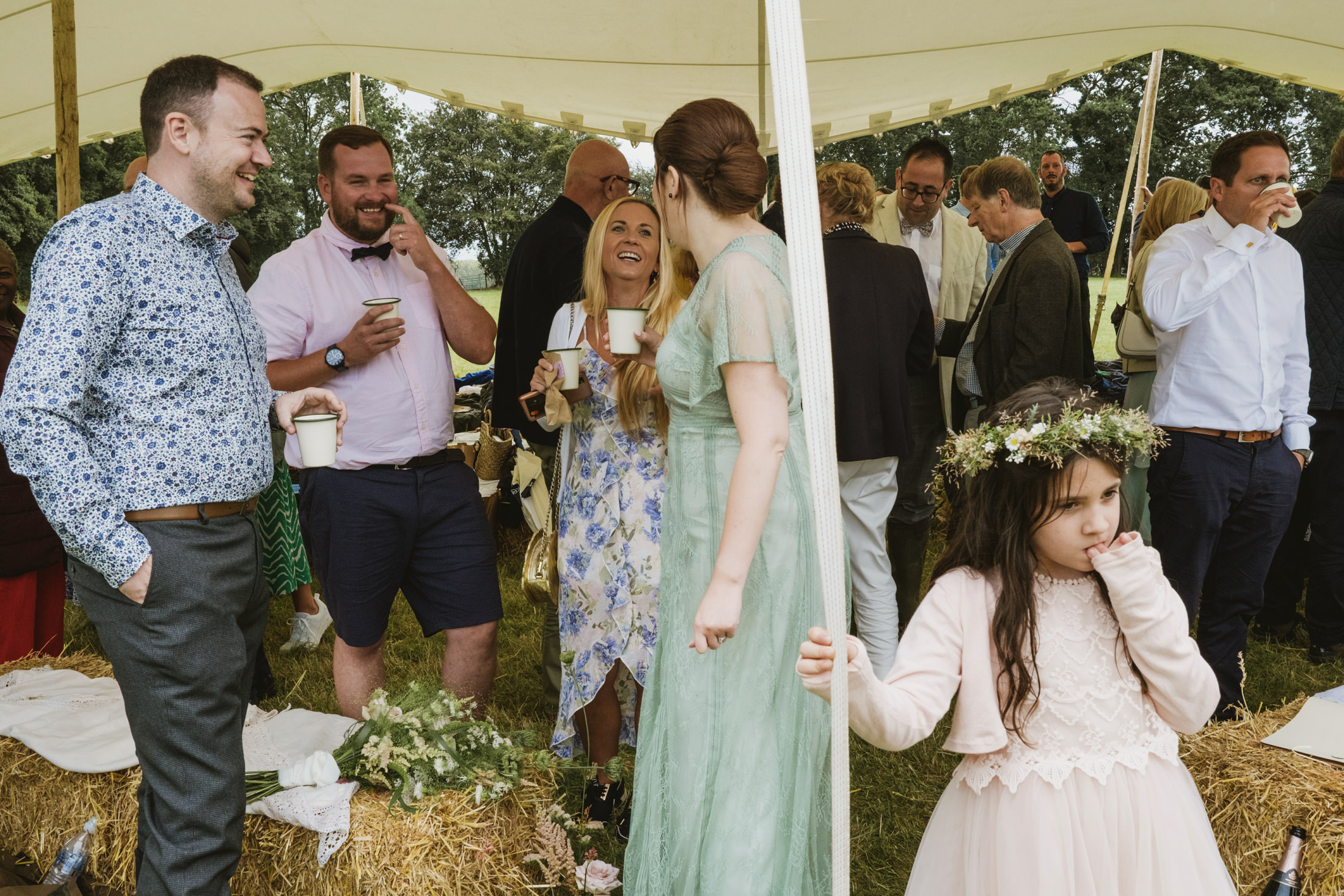 Guests socialising at outdoor event under marquee.