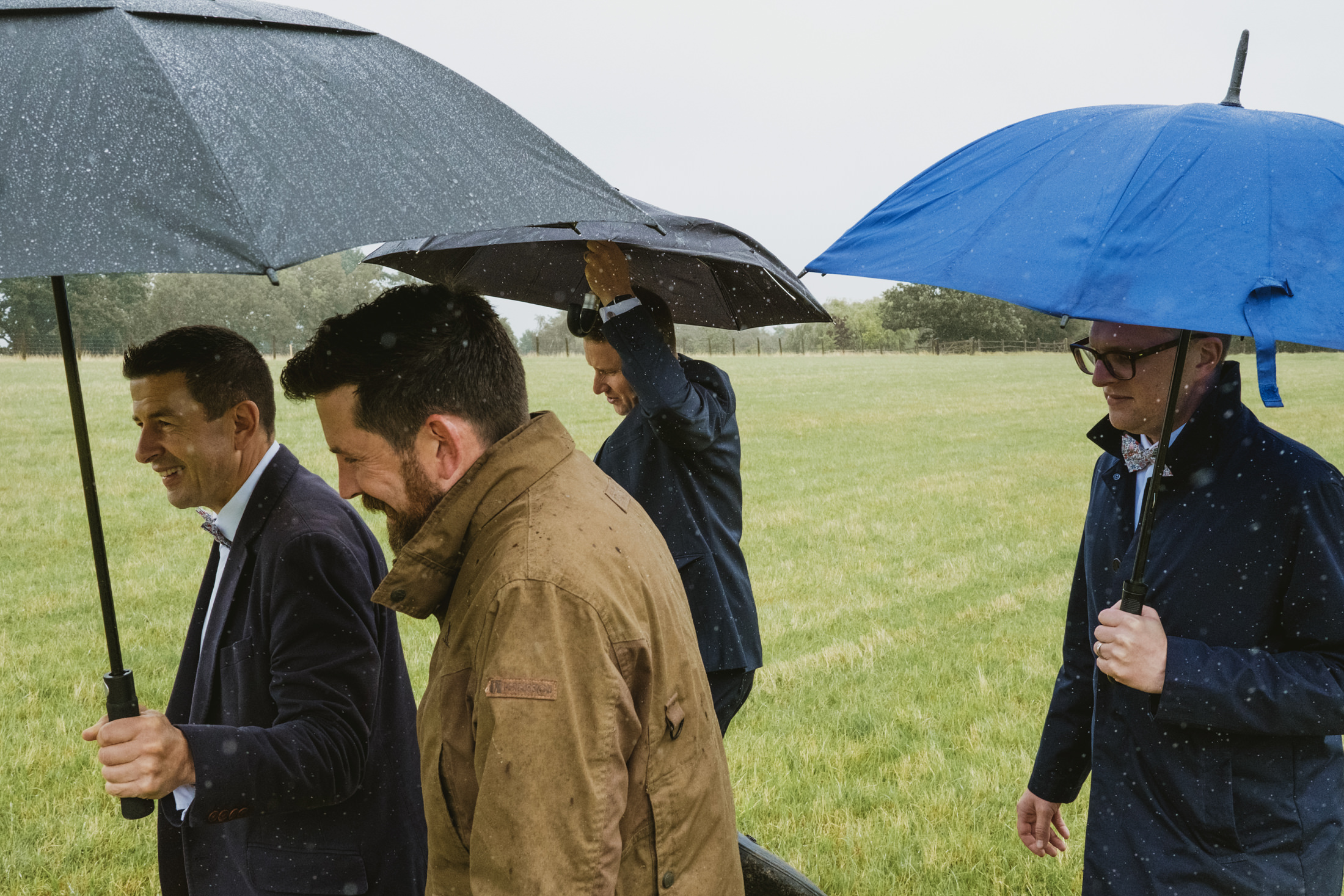 Four men walking in rain with umbrellas