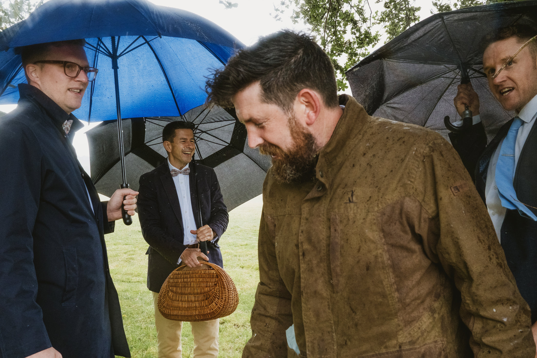 Group of men with umbrellas outdoors in rain.