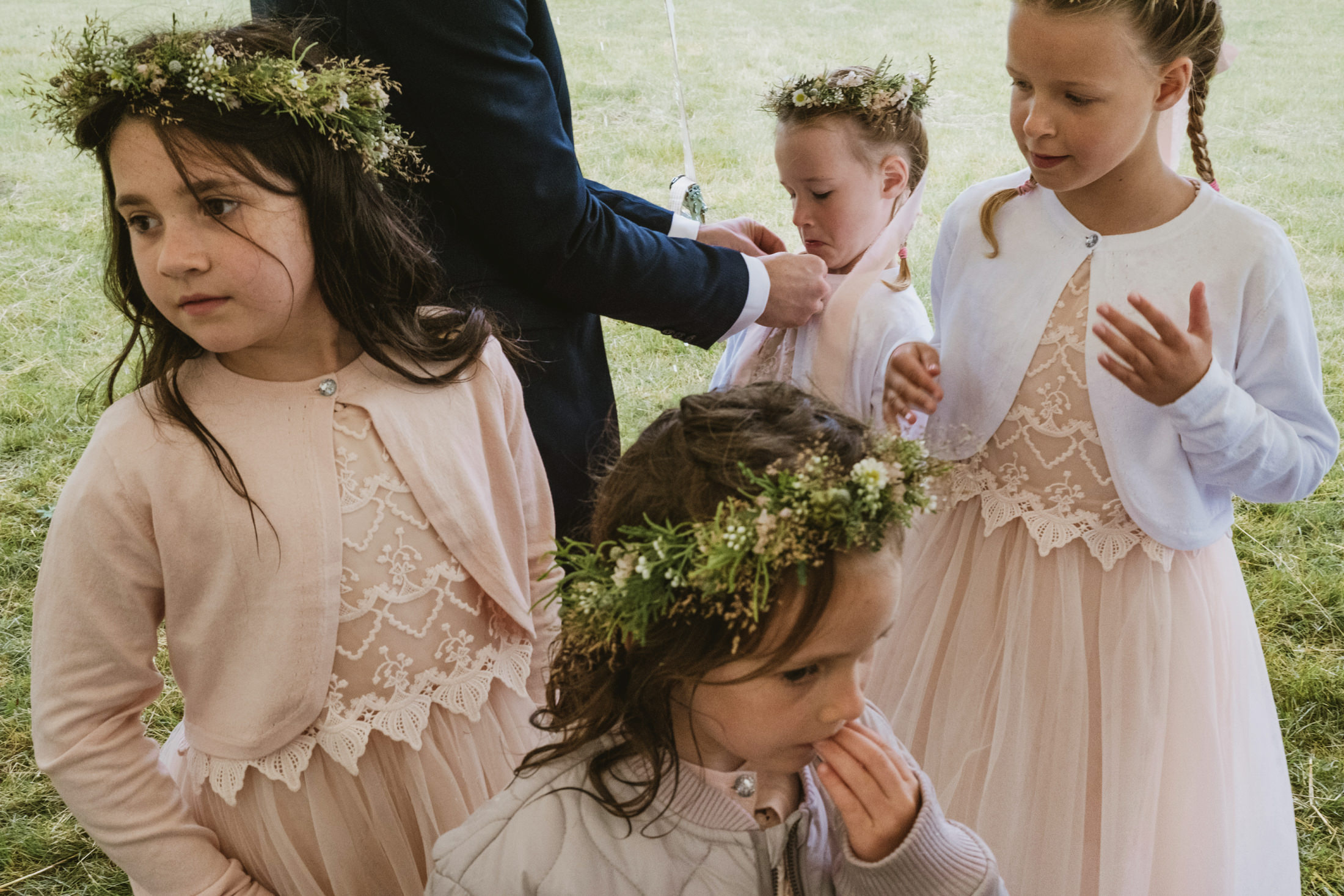 Children in floral crowns and dresses, outdoor setting.