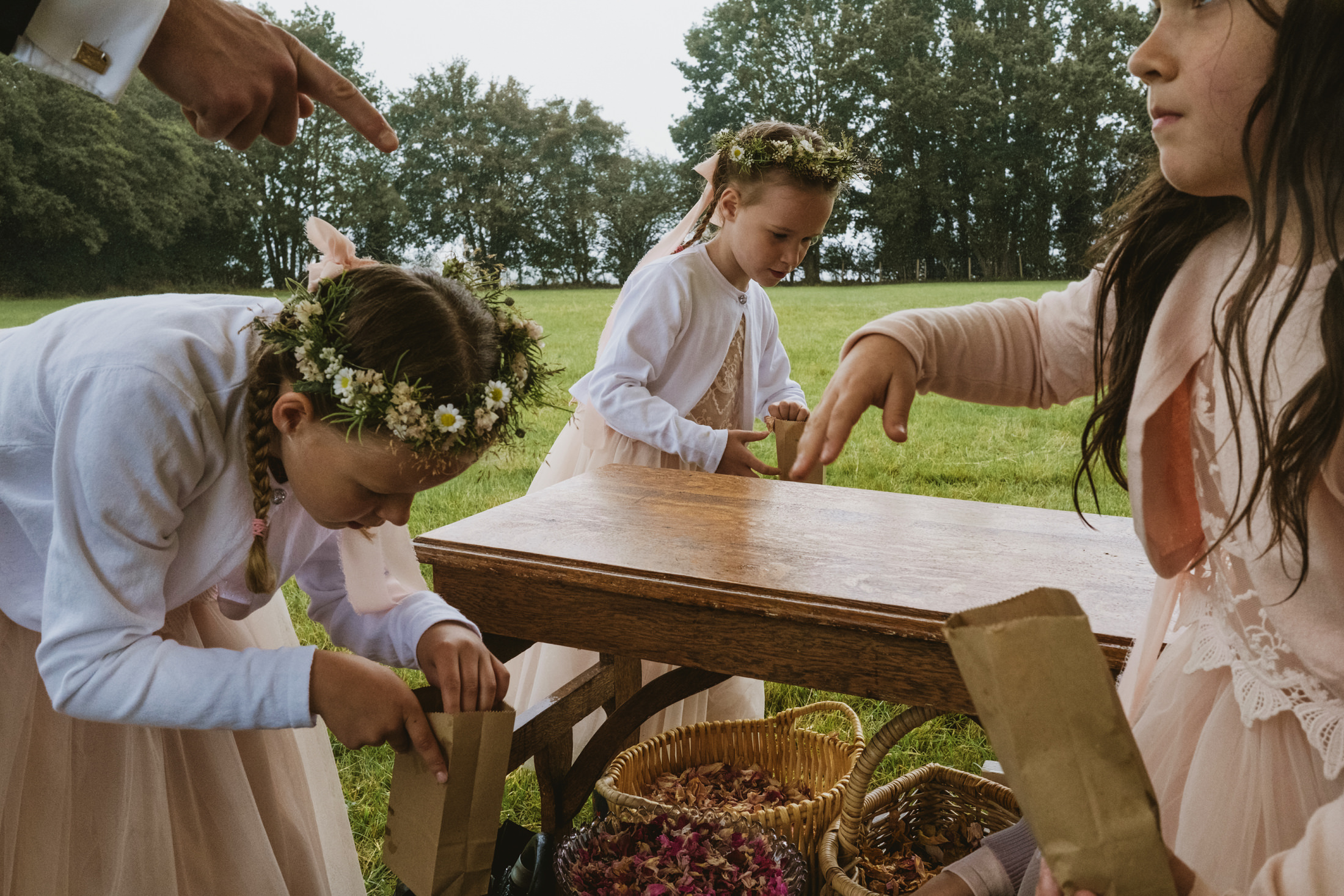 Children collecting flower petals in brown paper bags.
