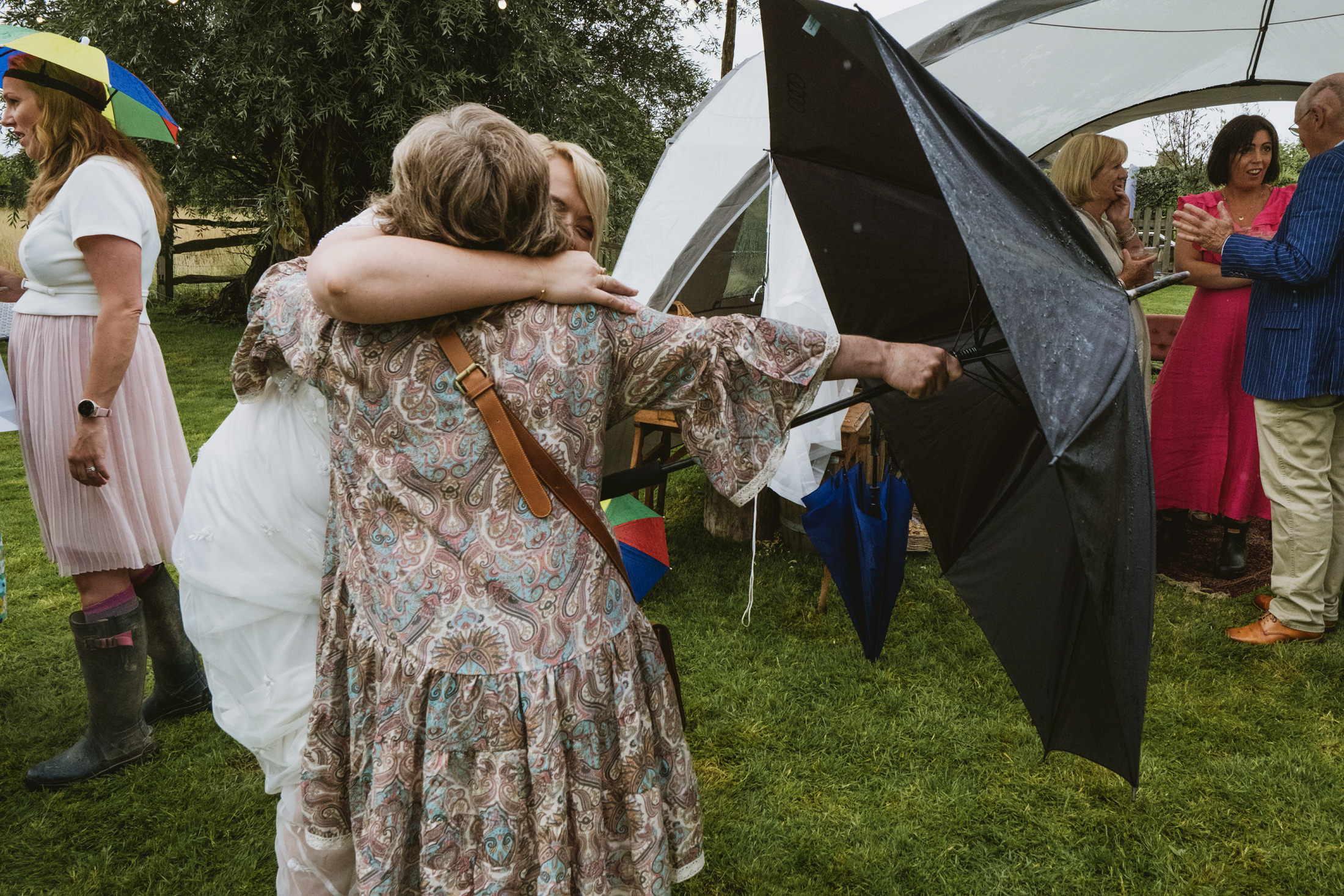 People hugging under an umbrella at outdoor event.