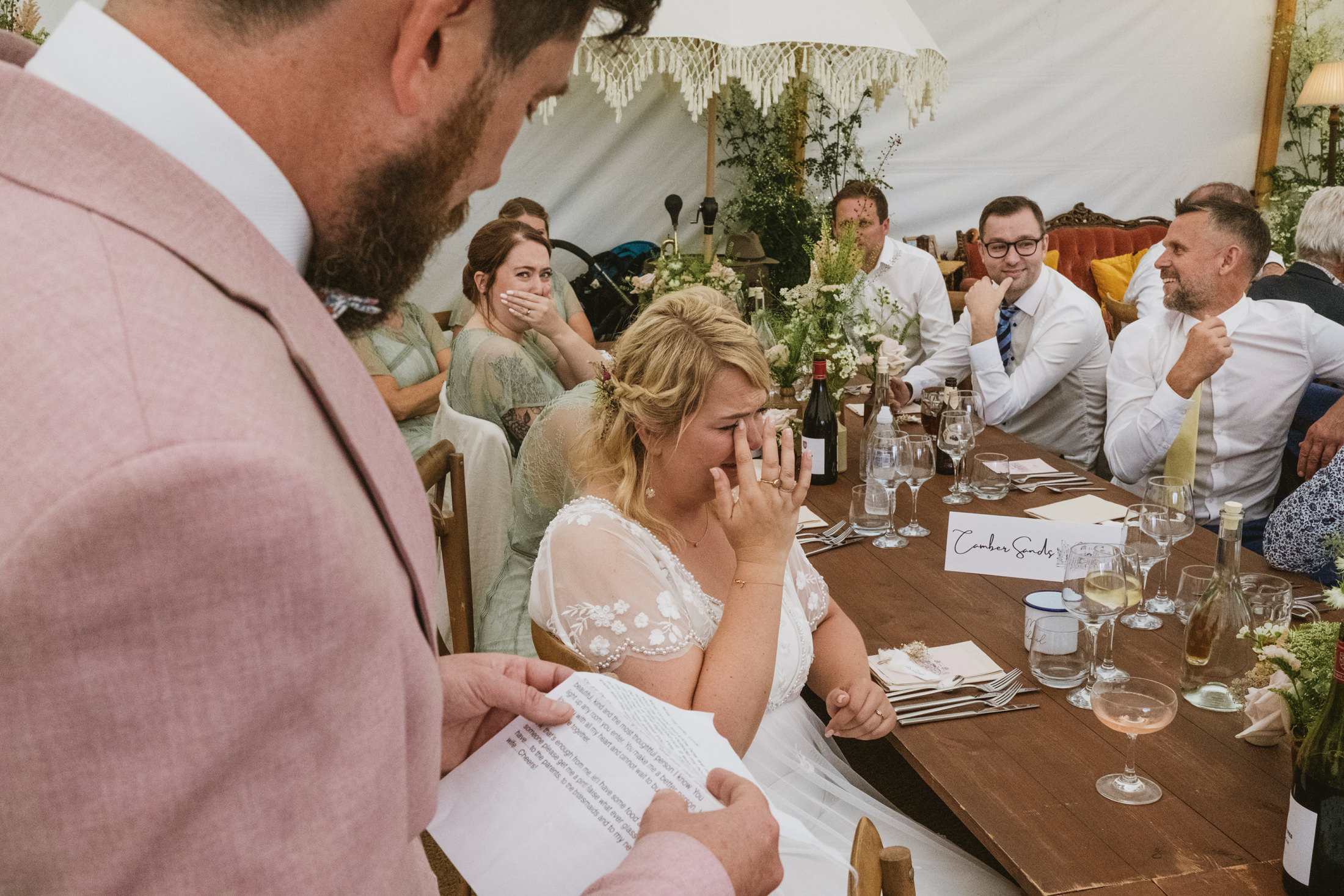 Bride crying at wedding speech, emotional guests around