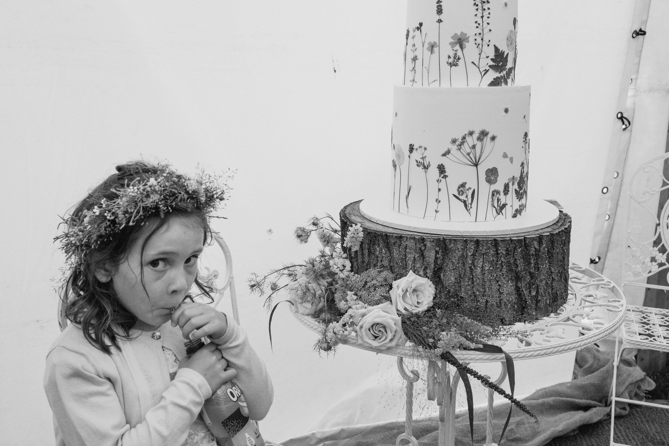 Girl with flower crown near wedding cake.