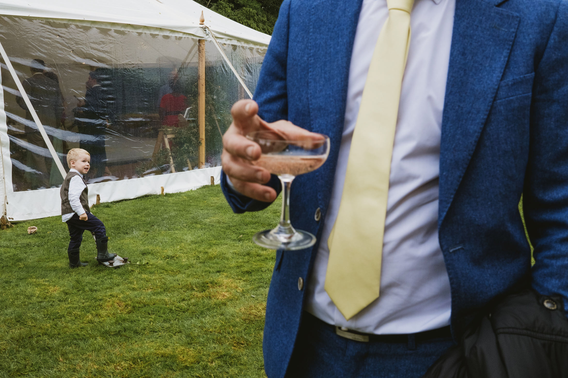 Man in blue suit holding champagne glass outdoors.