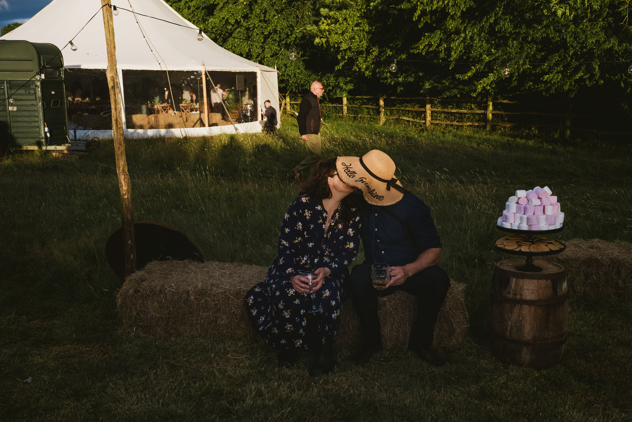 Couple kissing, outdoor event with hay bales.