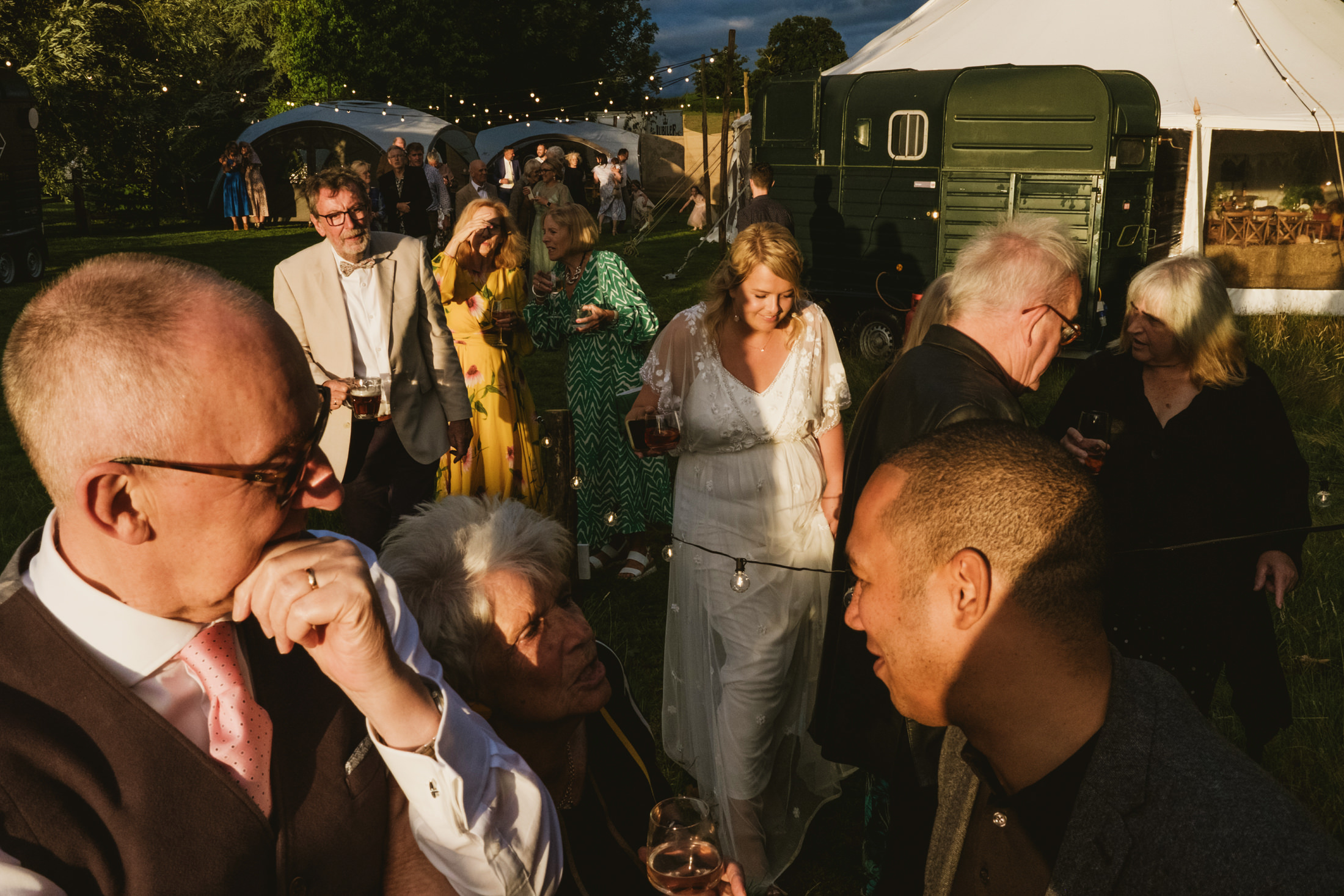 Outdoor wedding reception with guests socialising.