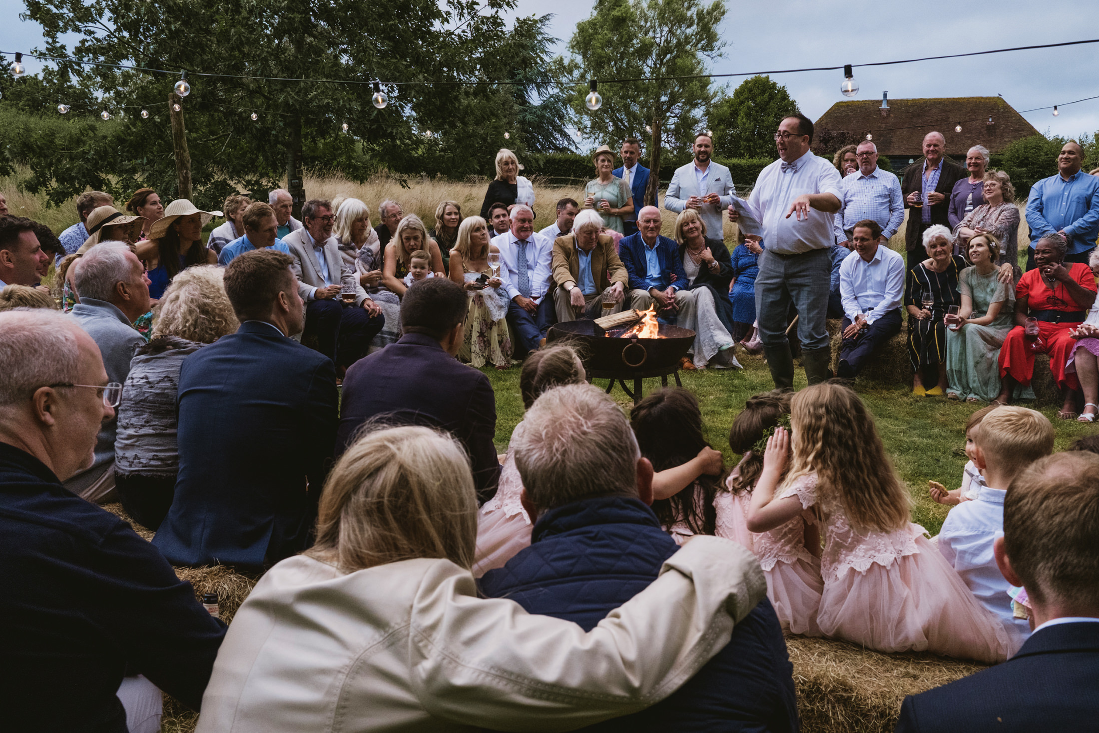 Outdoor gathering around a fire pit during summer evening.