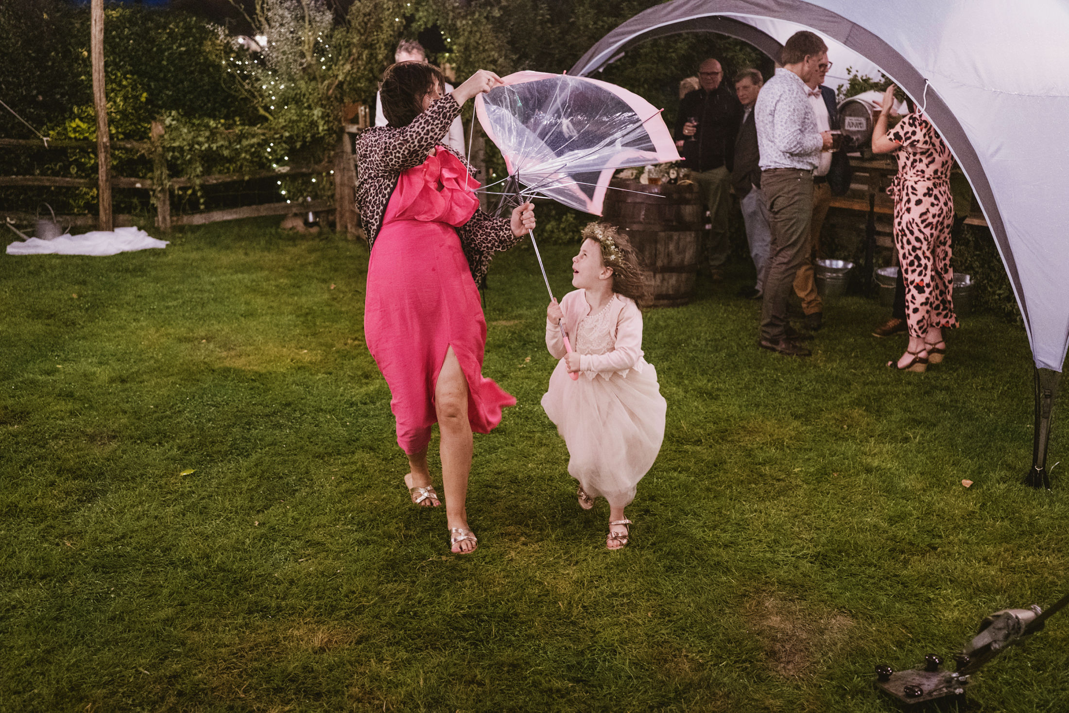 Woman and child dancing with umbrella at outdoor event.