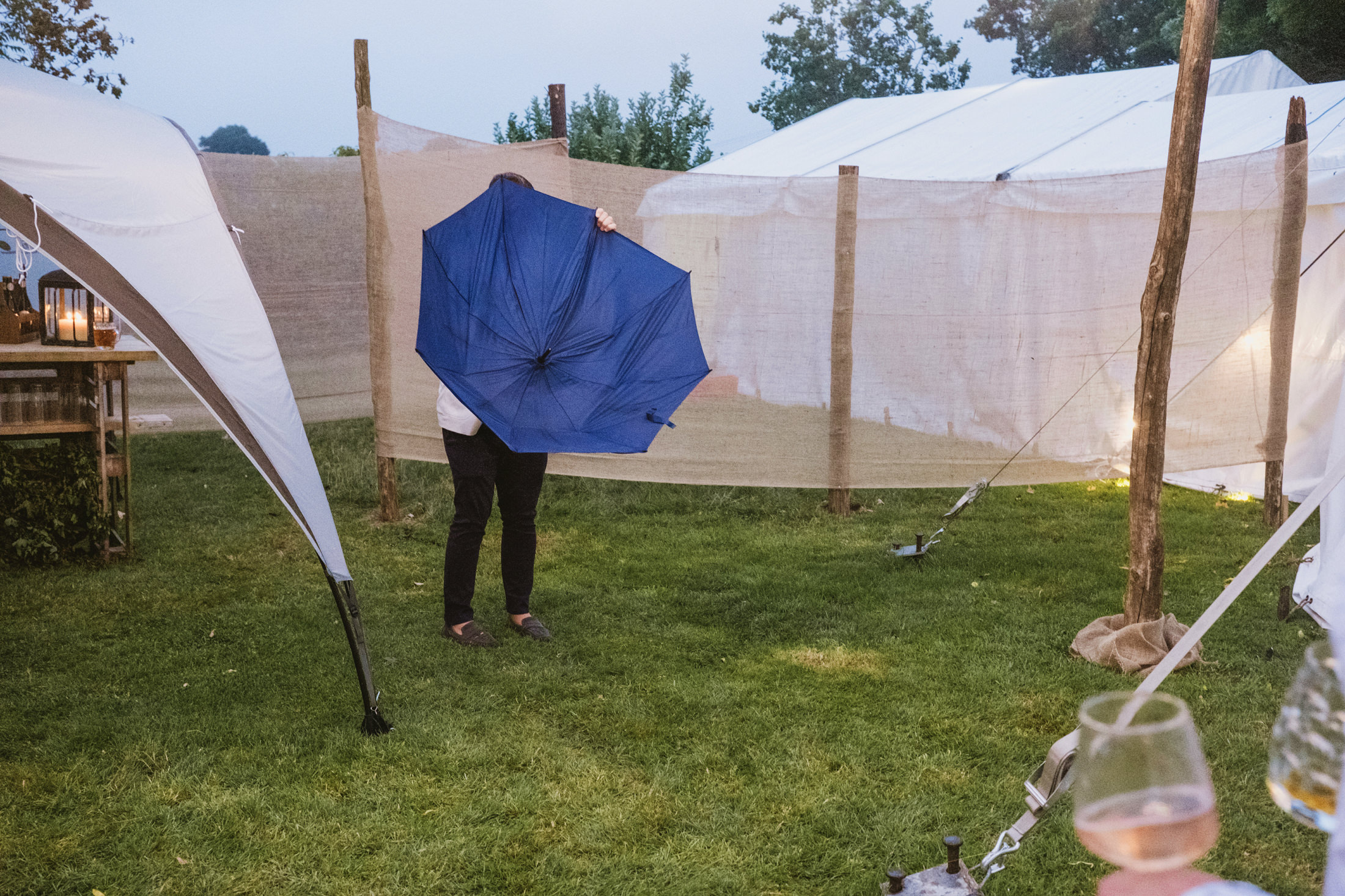 Person holding blue umbrella at outdoor event.