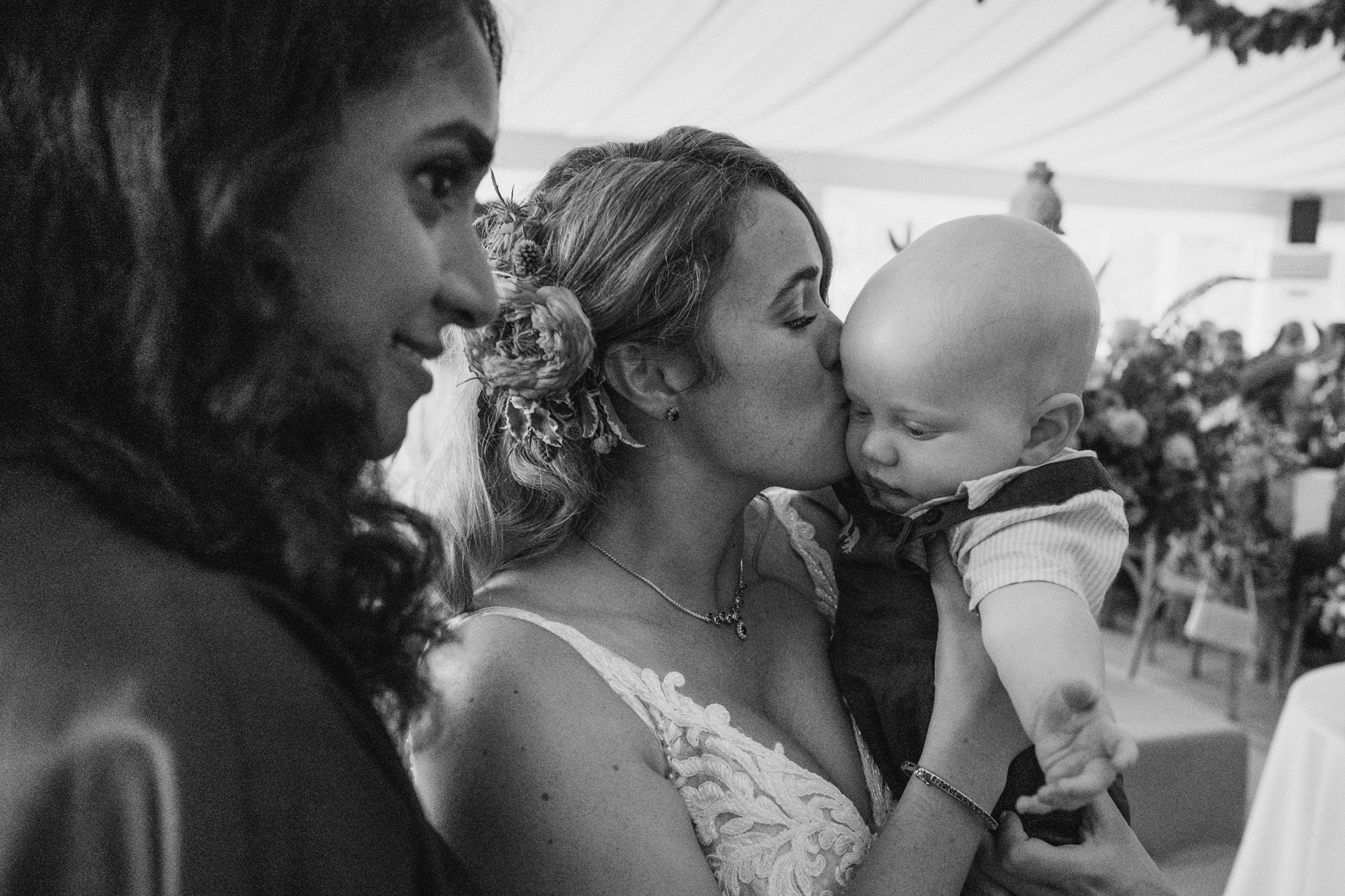Woman kissing baby at wedding celebration.