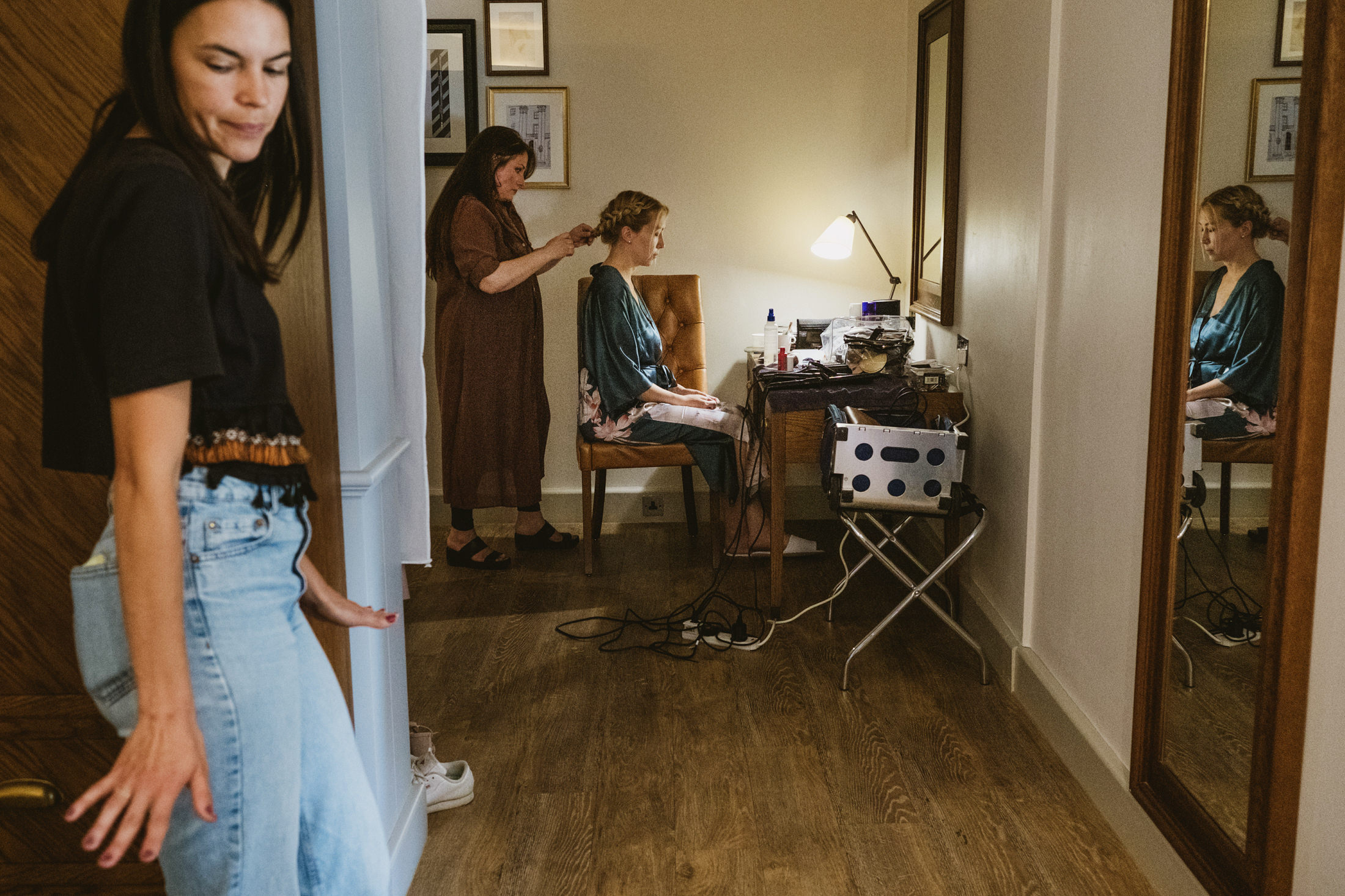Woman preparing bride's hair in dressing room.
