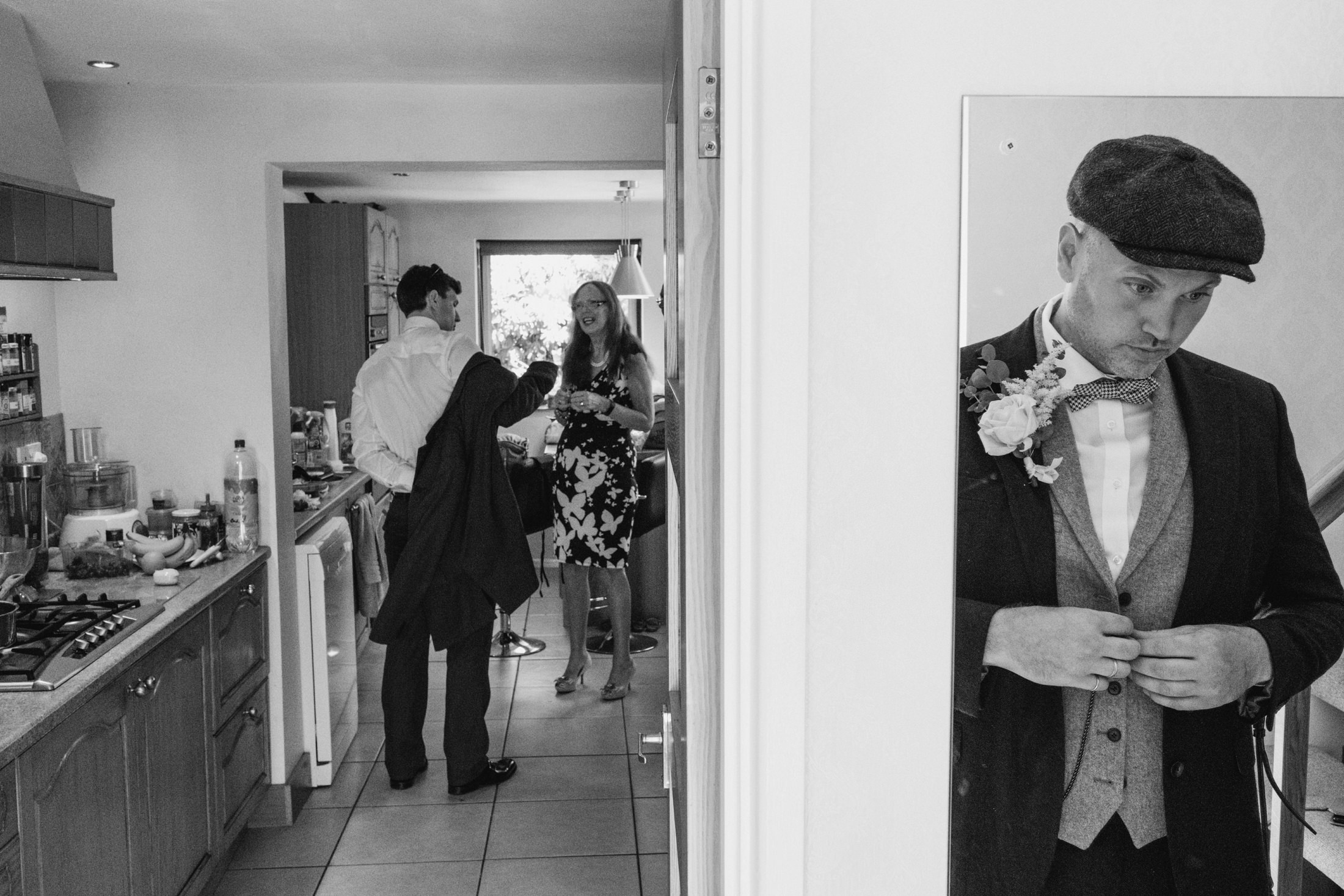 Man in suit reflected in mirror; people talking.