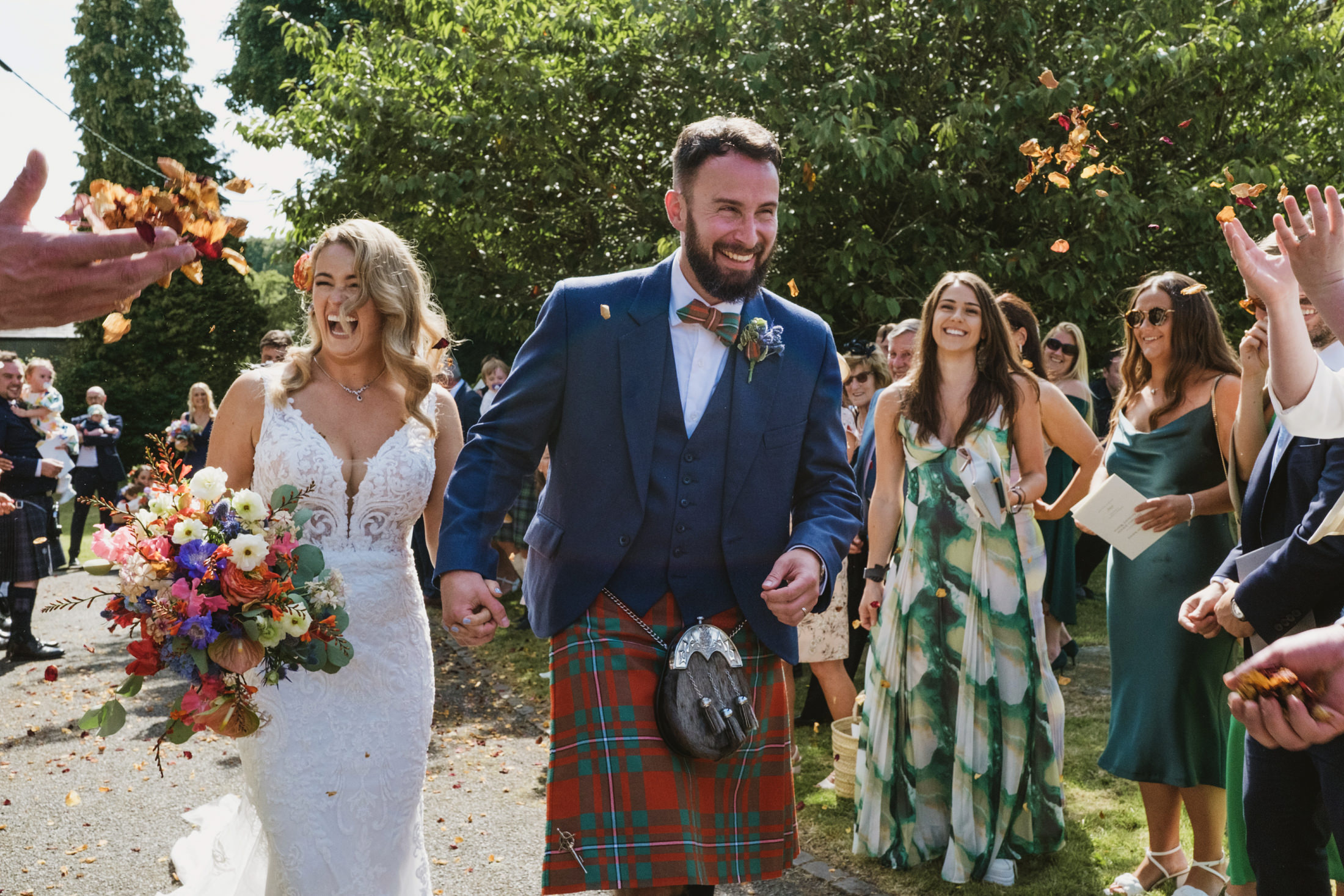 Happy couple exit wedding with flower confetti.