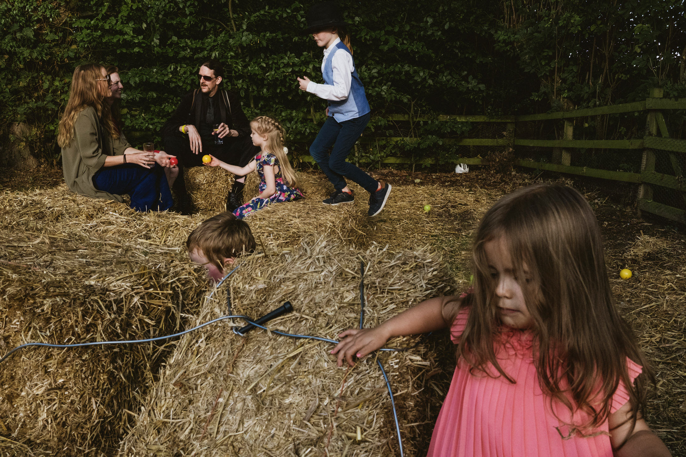 Children and adults playing on hay bales.
