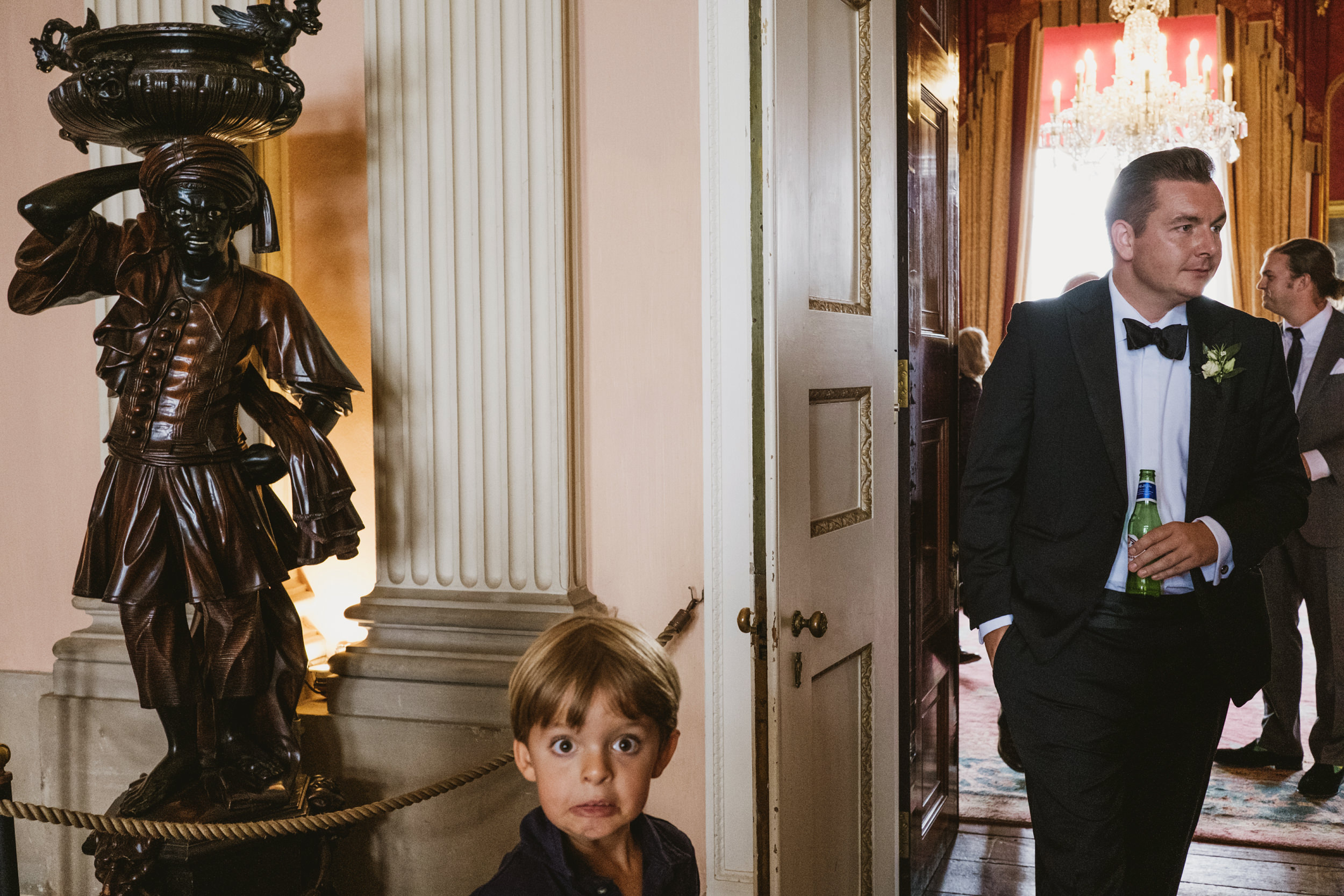 Child surprised, man with drink, decorative statue indoors.