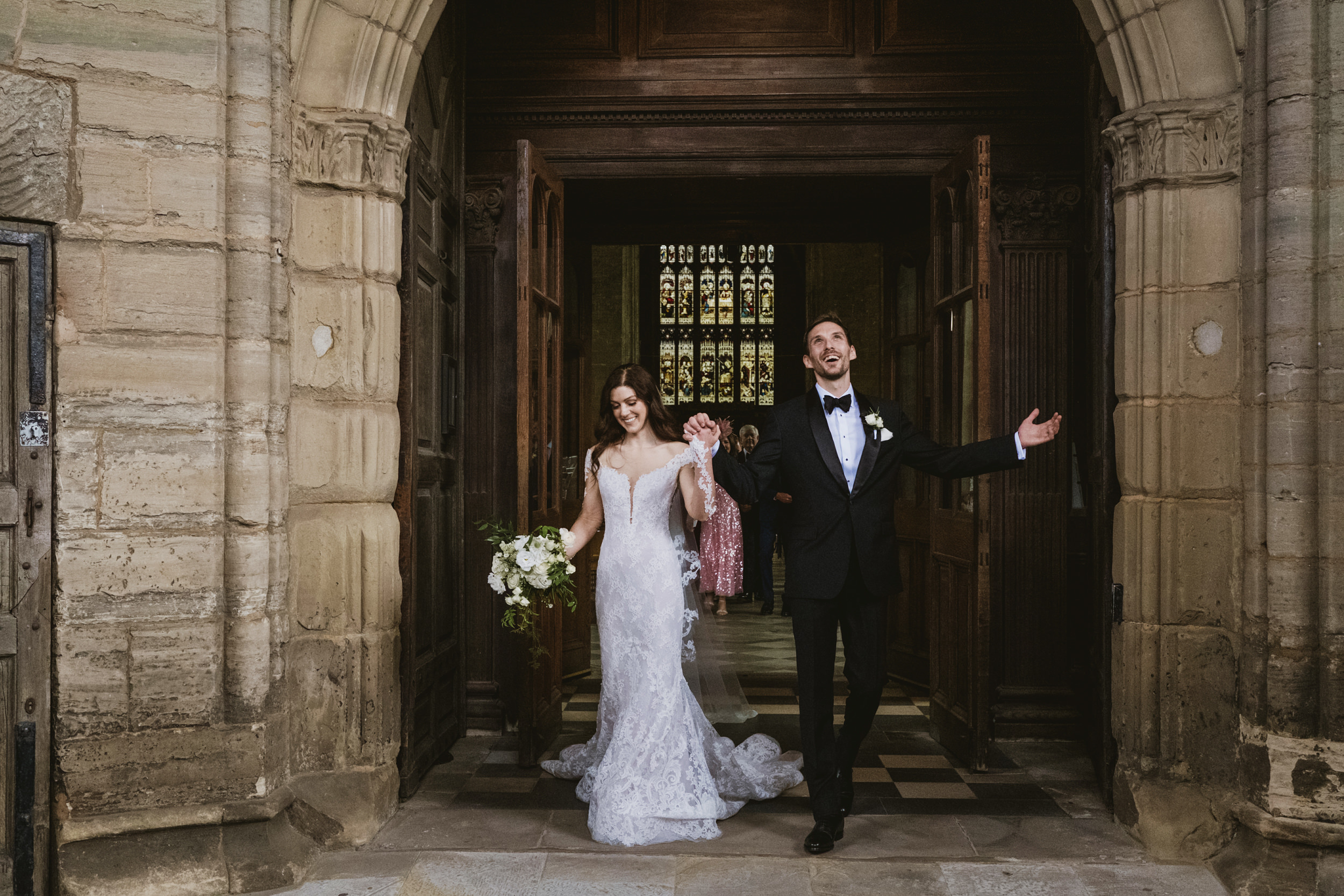 Newlyweds exiting church, holding hands joyfully.