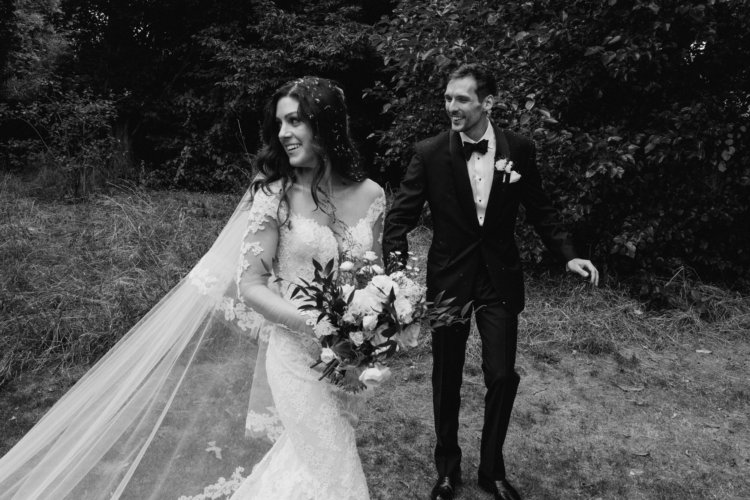 Bride and groom walking outdoors in wedding attire.