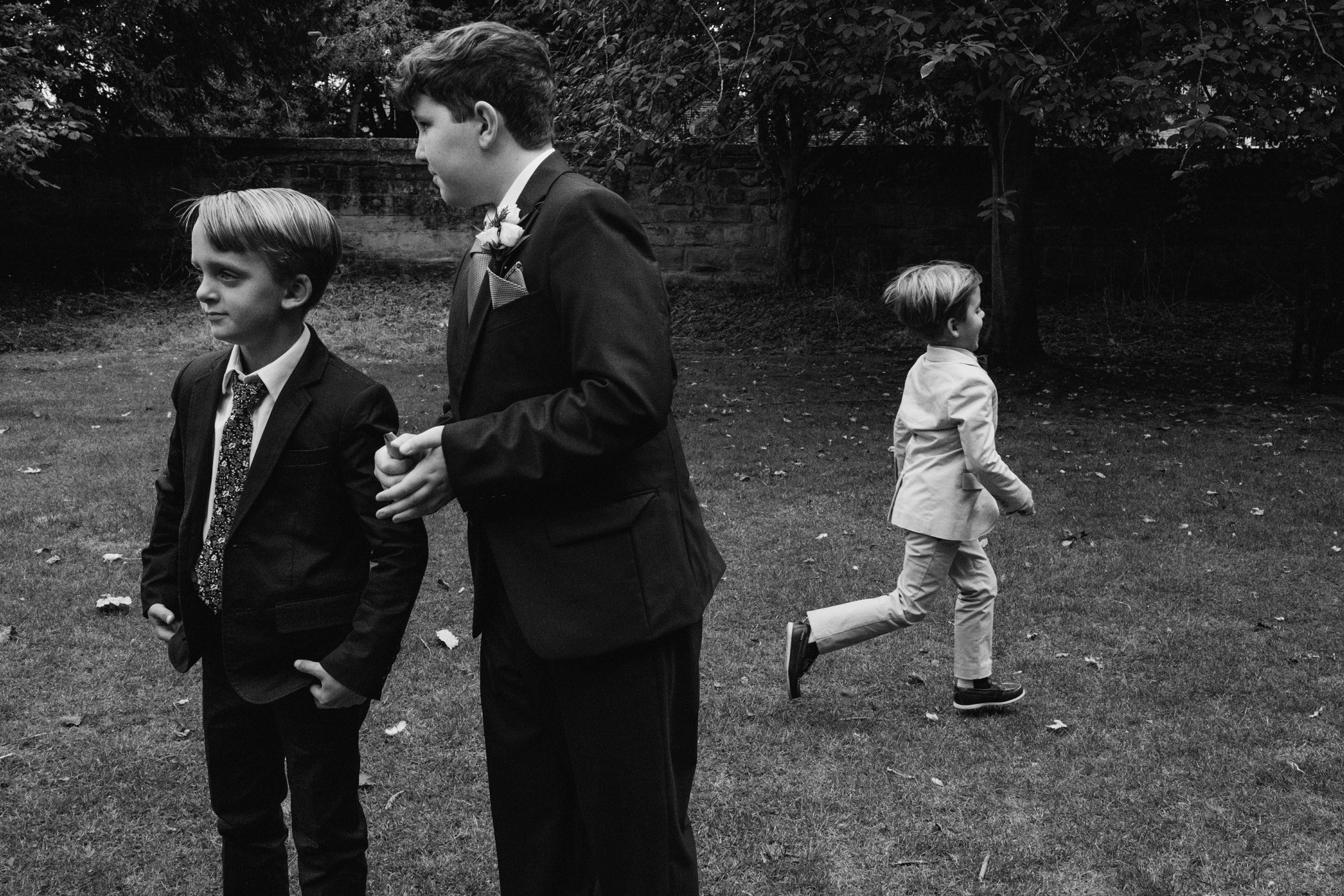 Three boys in suits playing on grass