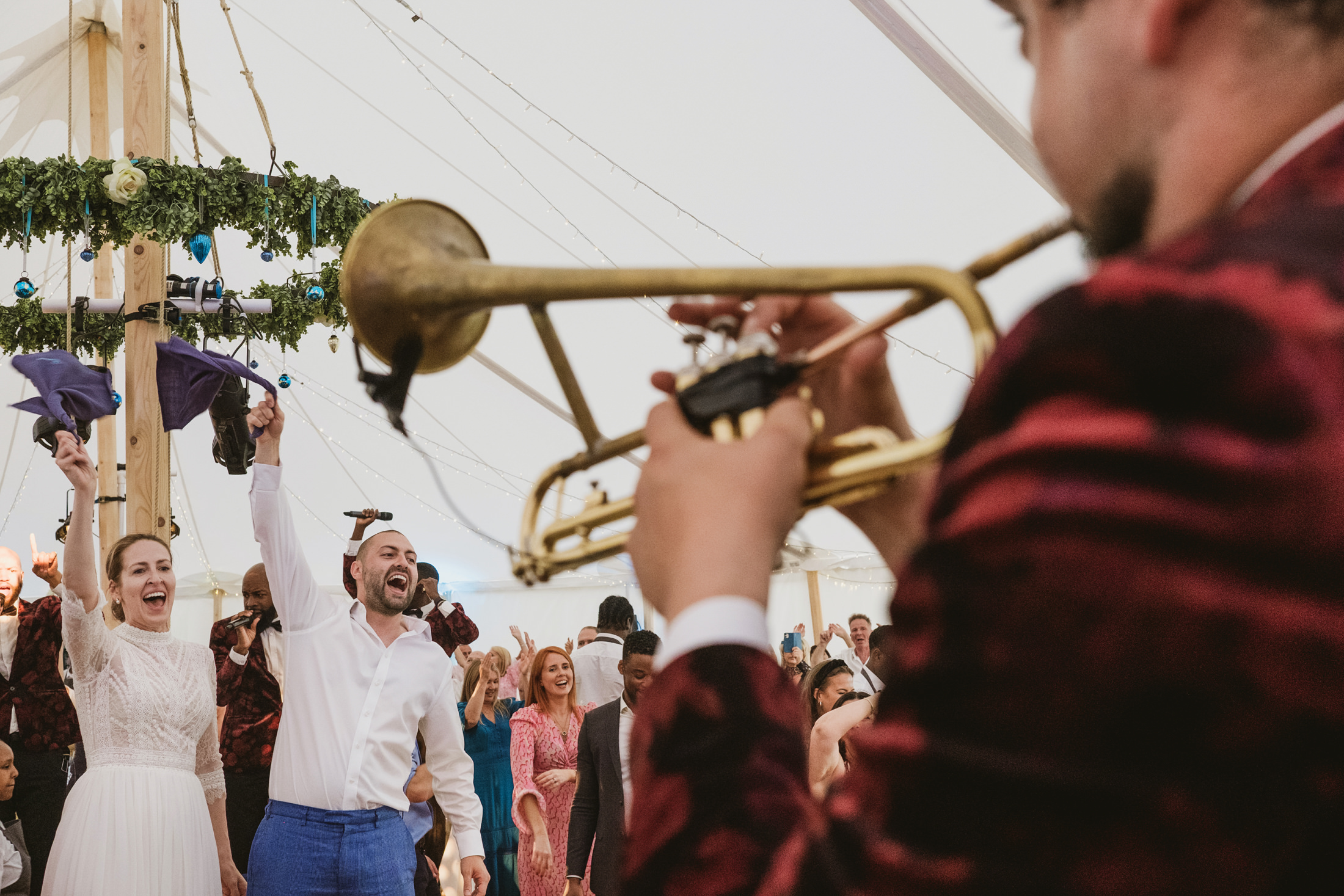 Wedding celebration with trumpet player and dancing guests.