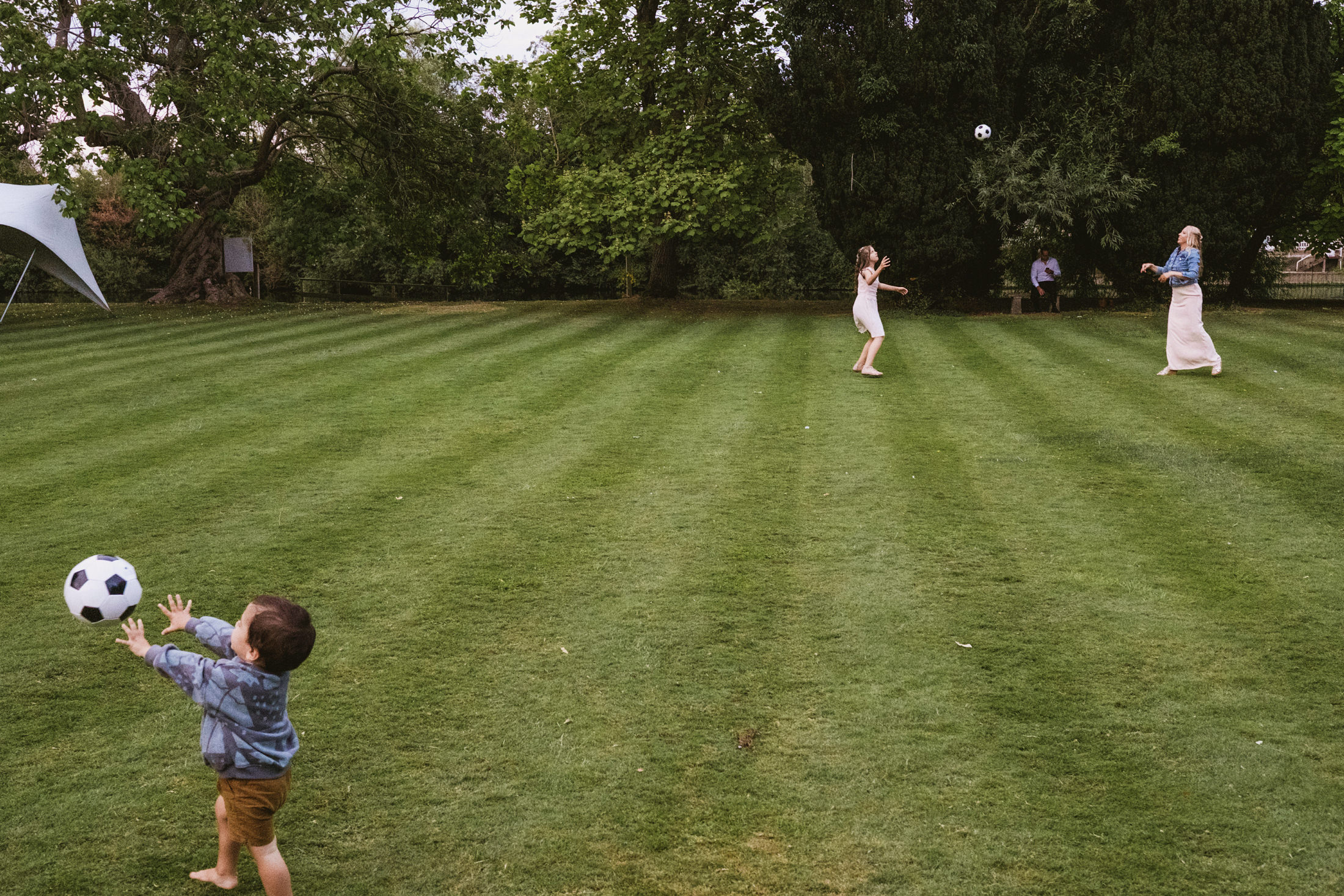 Children playing with a football on grass lawn.