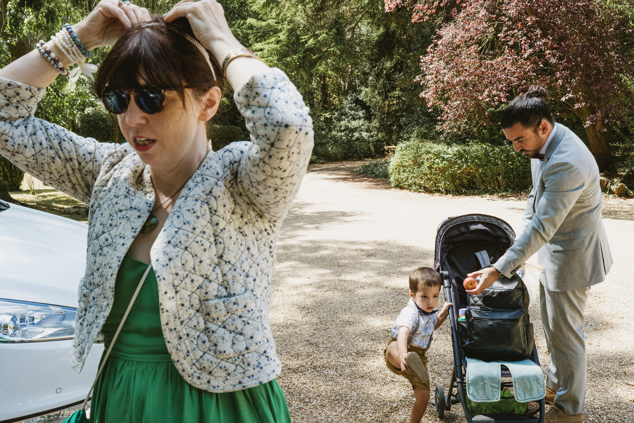 Family outdoors with pram and child playing.
