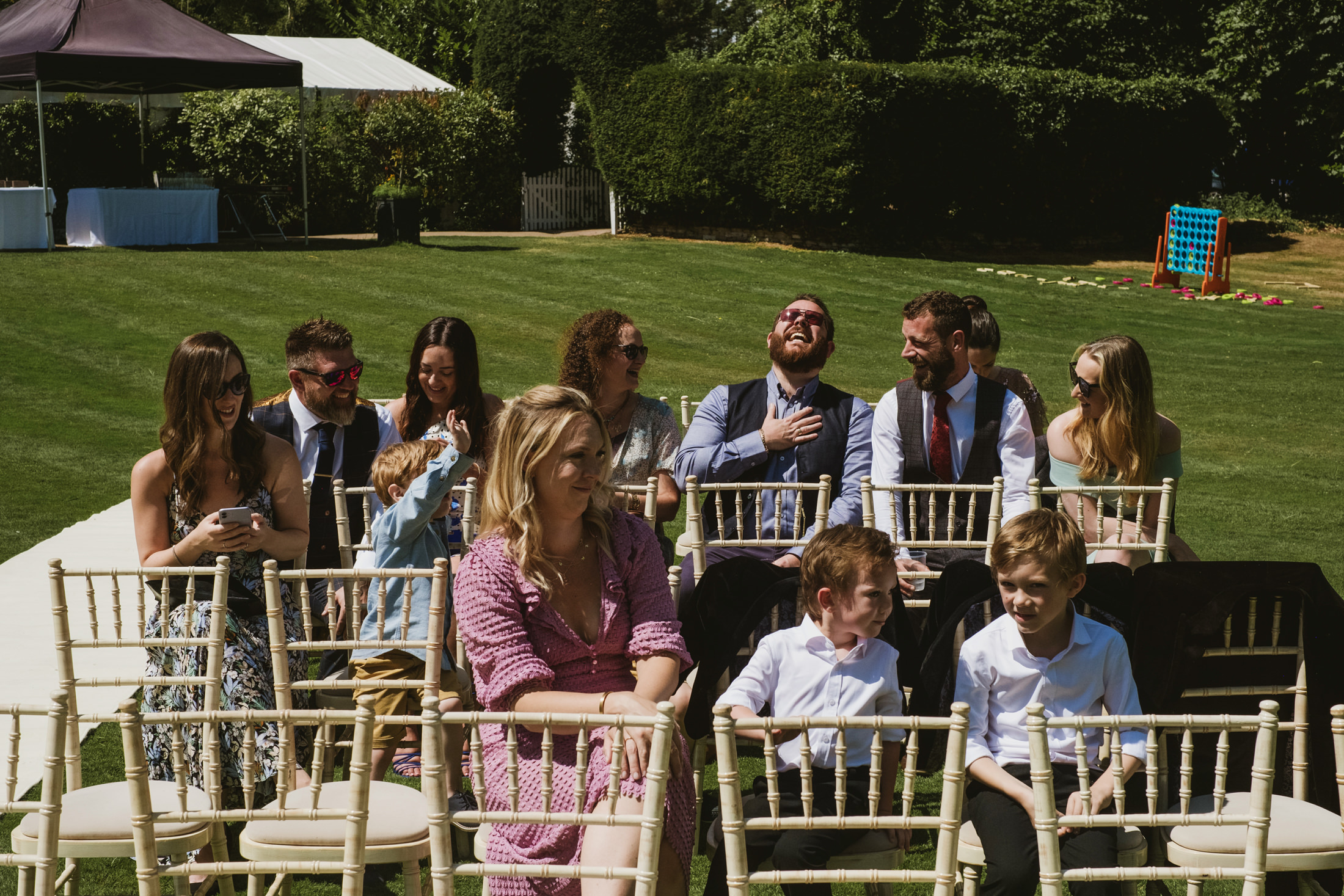 Guests laughing at outdoor gathering under sunny weather.