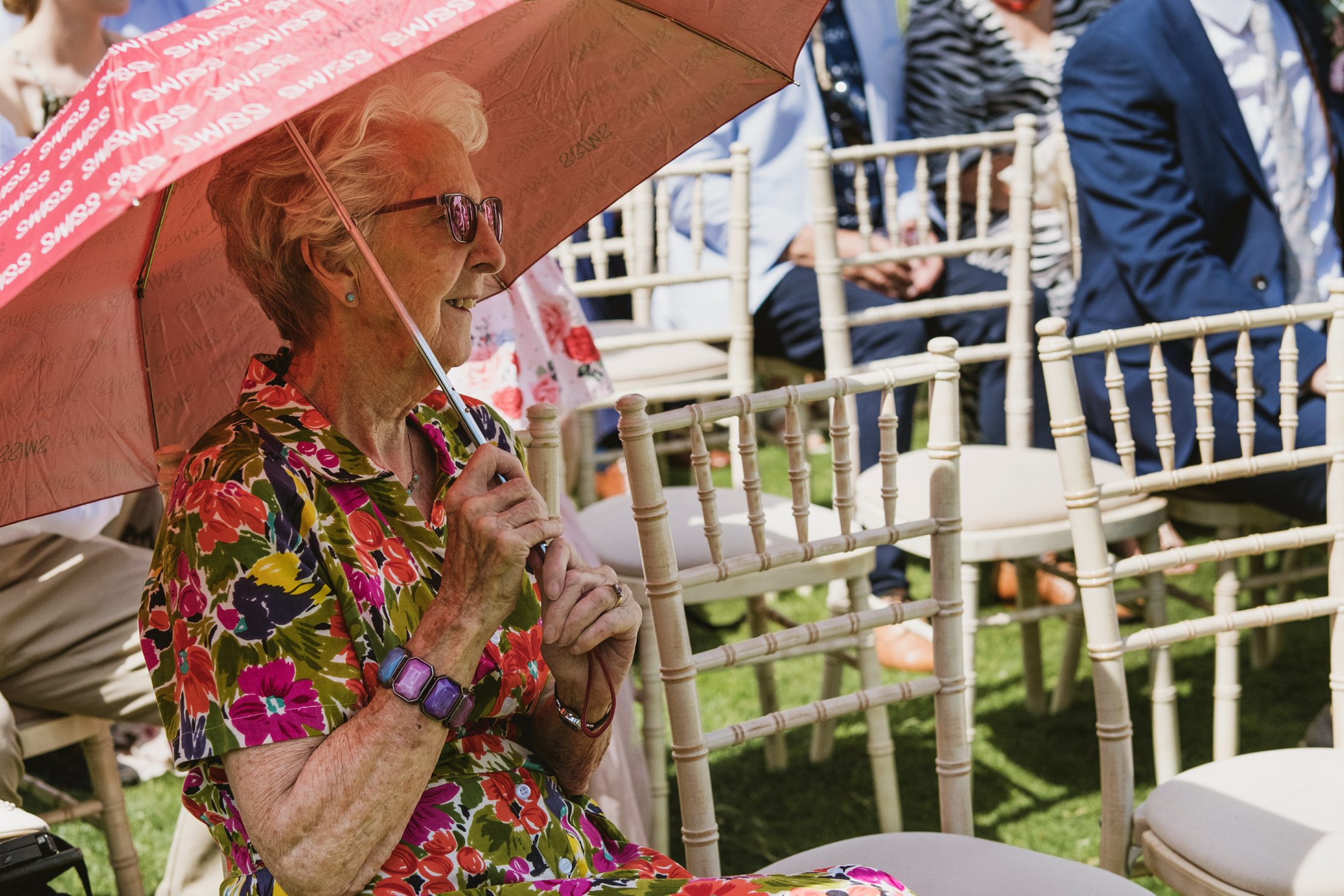 Elderly woman holding umbrella at outdoor event