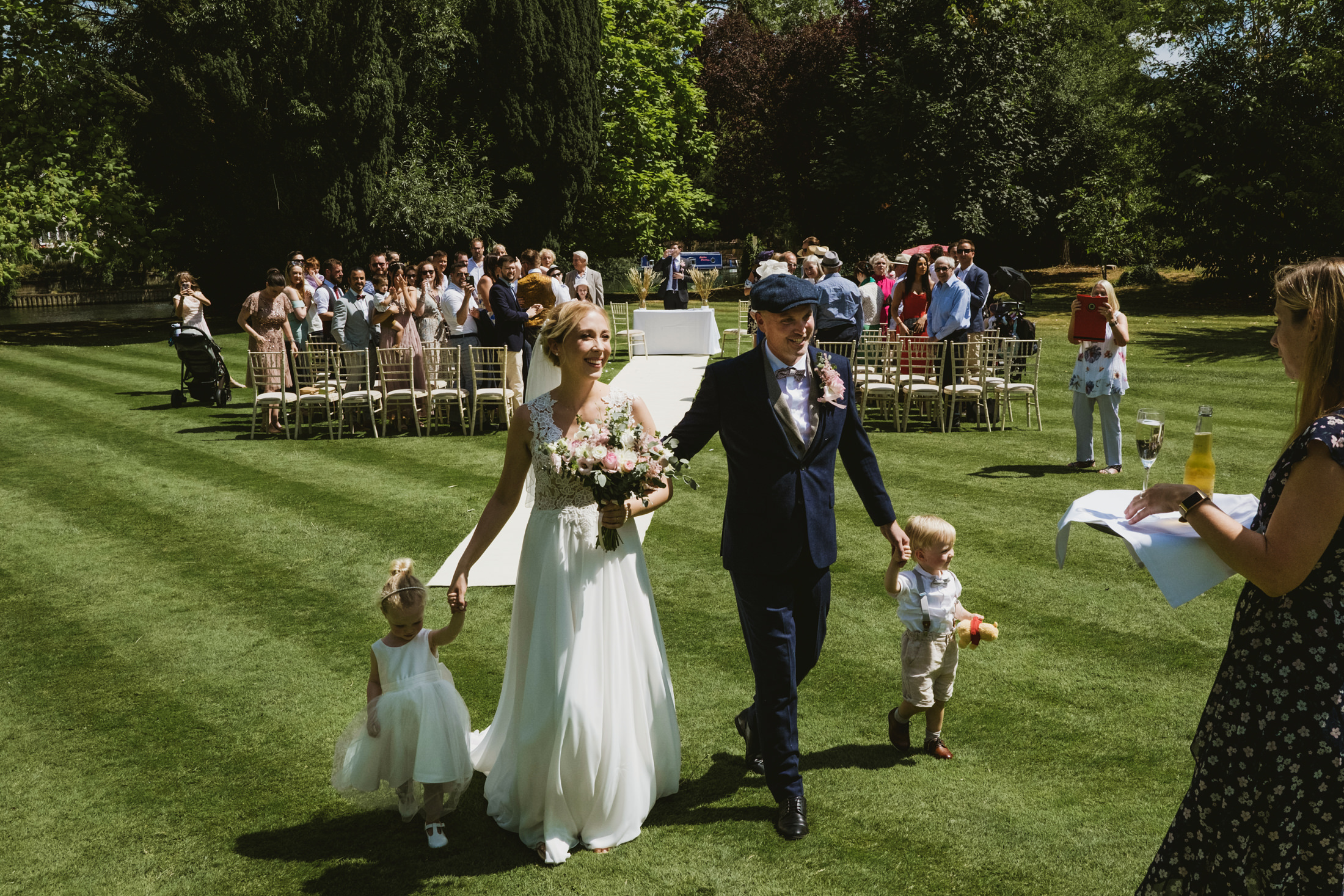 Outdoor wedding, couple walking hand-in-hand with children.