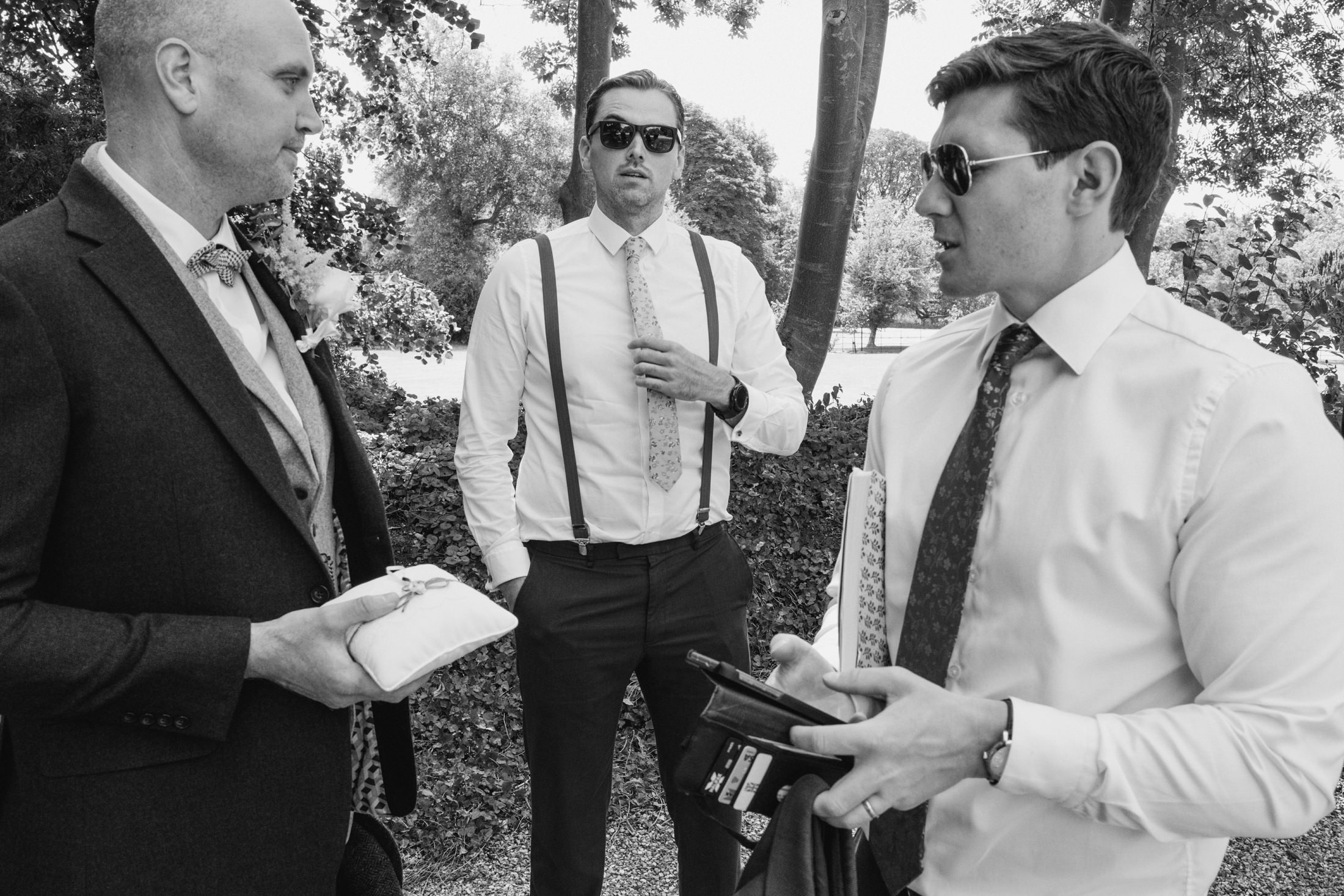 Men in formal attire talking outdoors at wedding