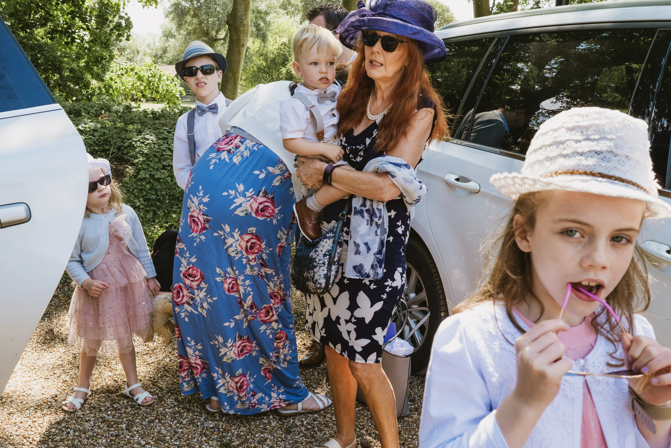 Family dressed up next to white car outdoors.