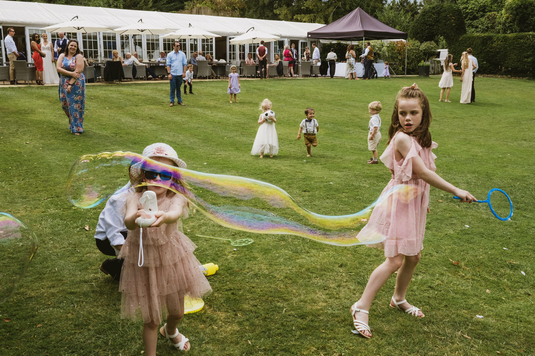 Documentary wedding photography at Riverside Marquee featuring children playing in the gardens; finding truth in the chaos.