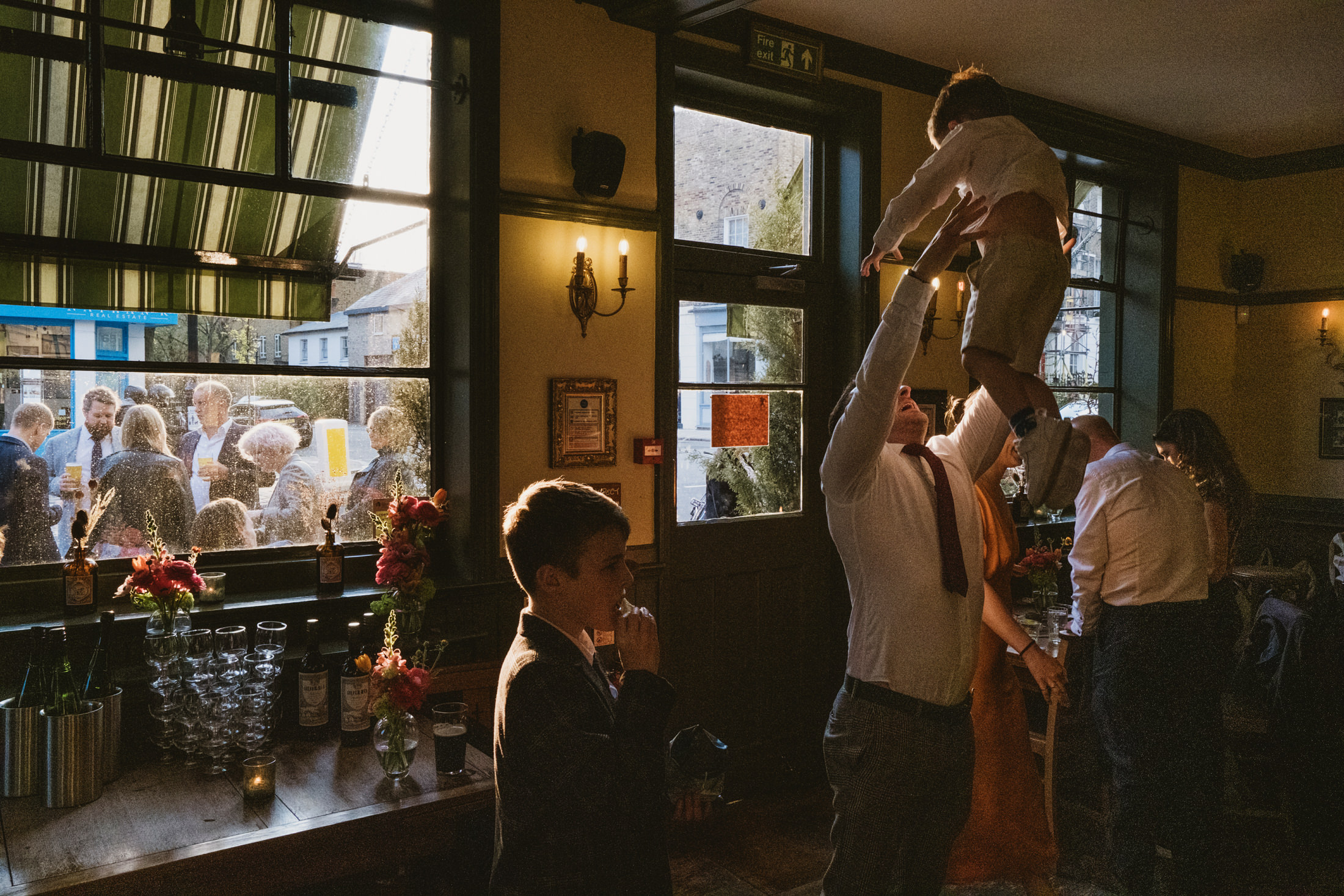 Family gathering inside pub, sunlight streaming through window.