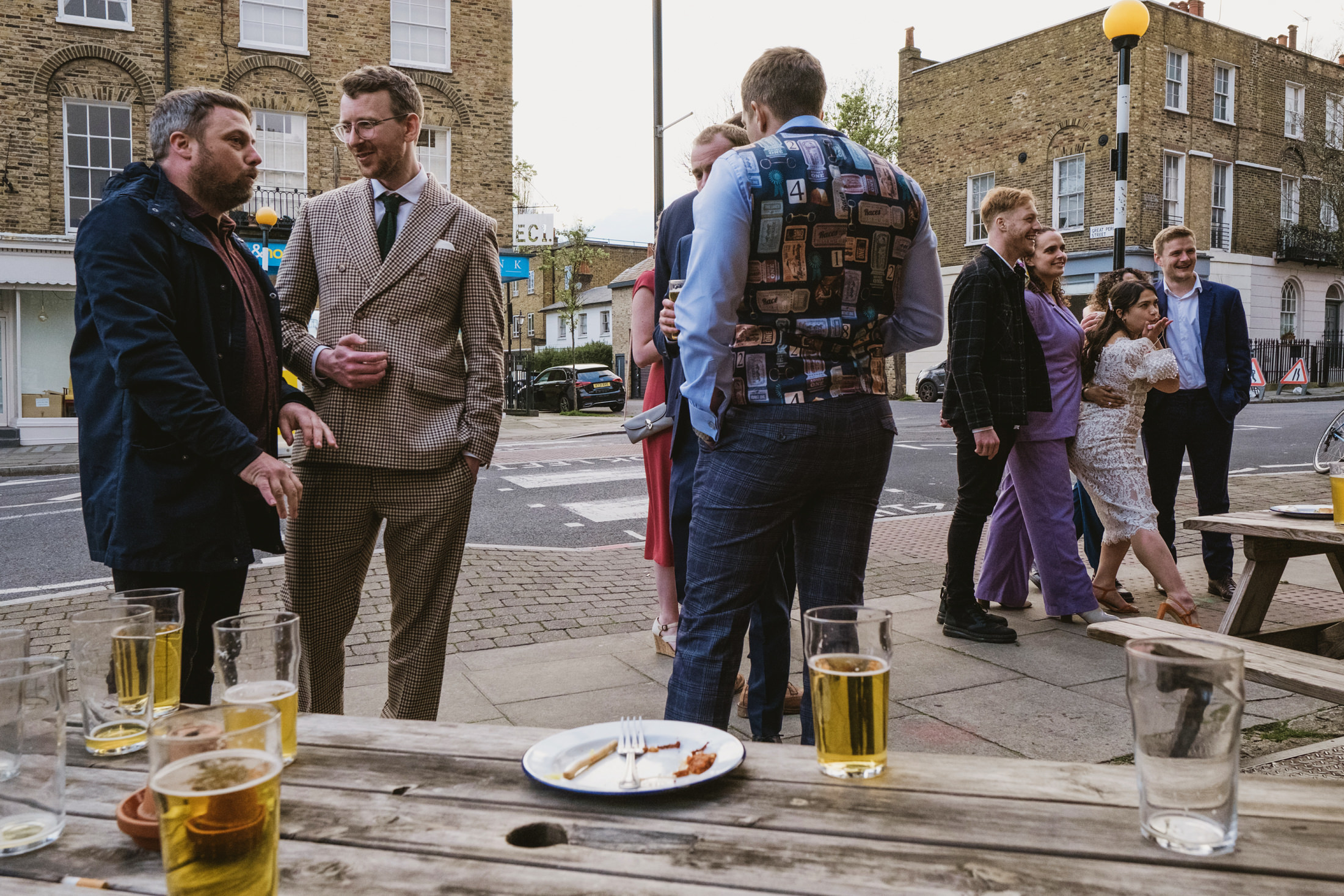 People socialising outside pub with drinks on table.