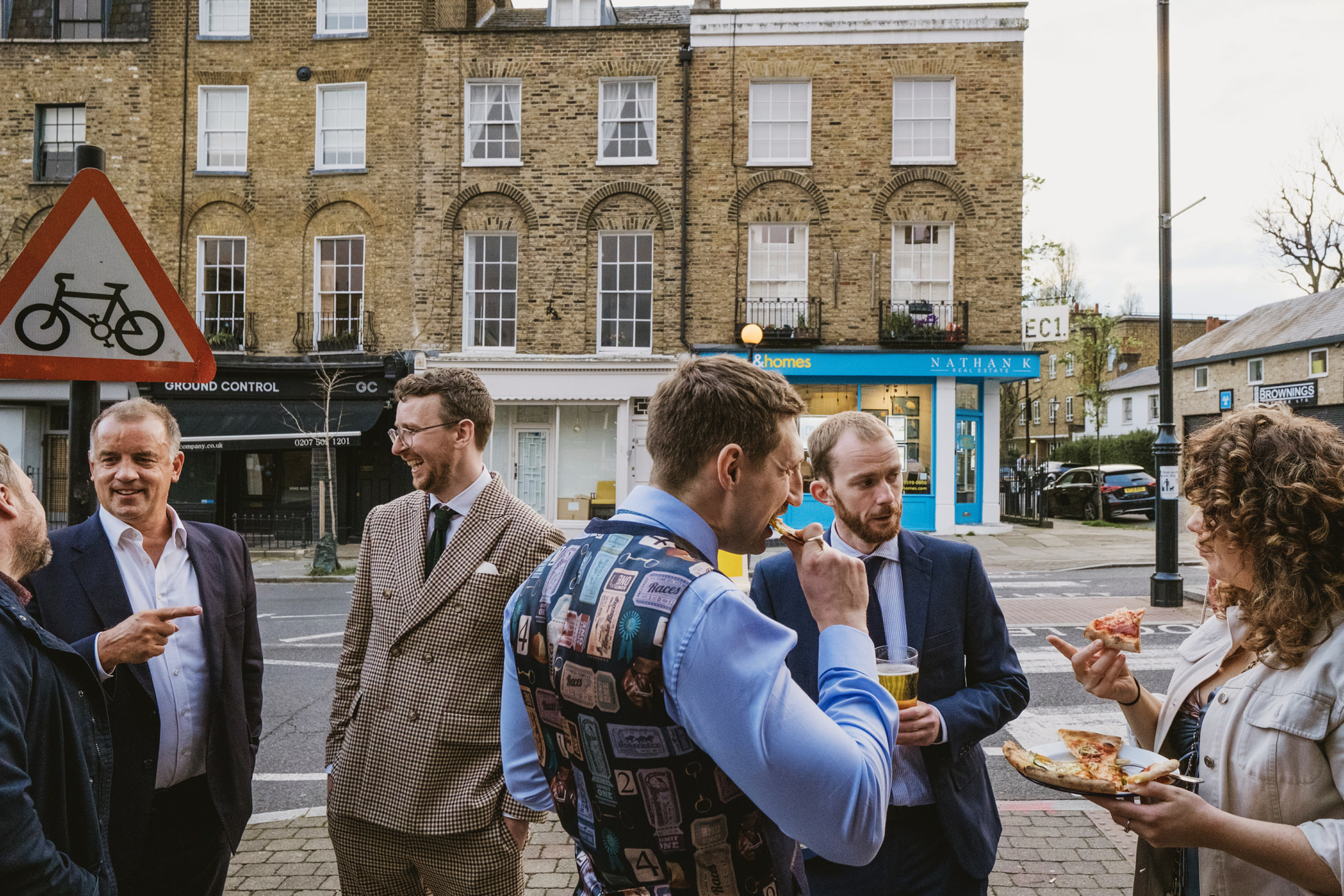 Group eating pizza outside in urban setting.