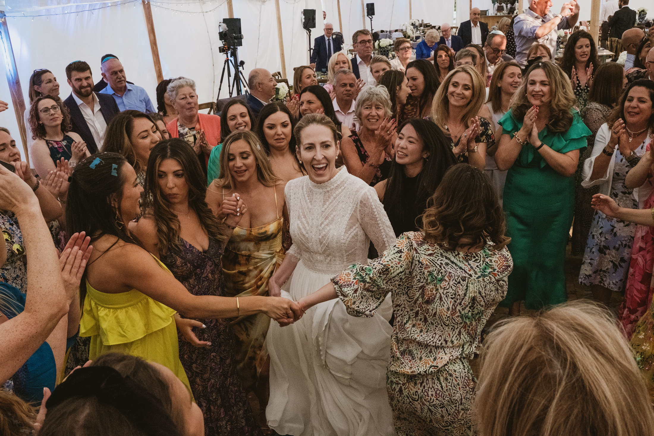 Bride dancing joyfully surrounded by wedding guests.