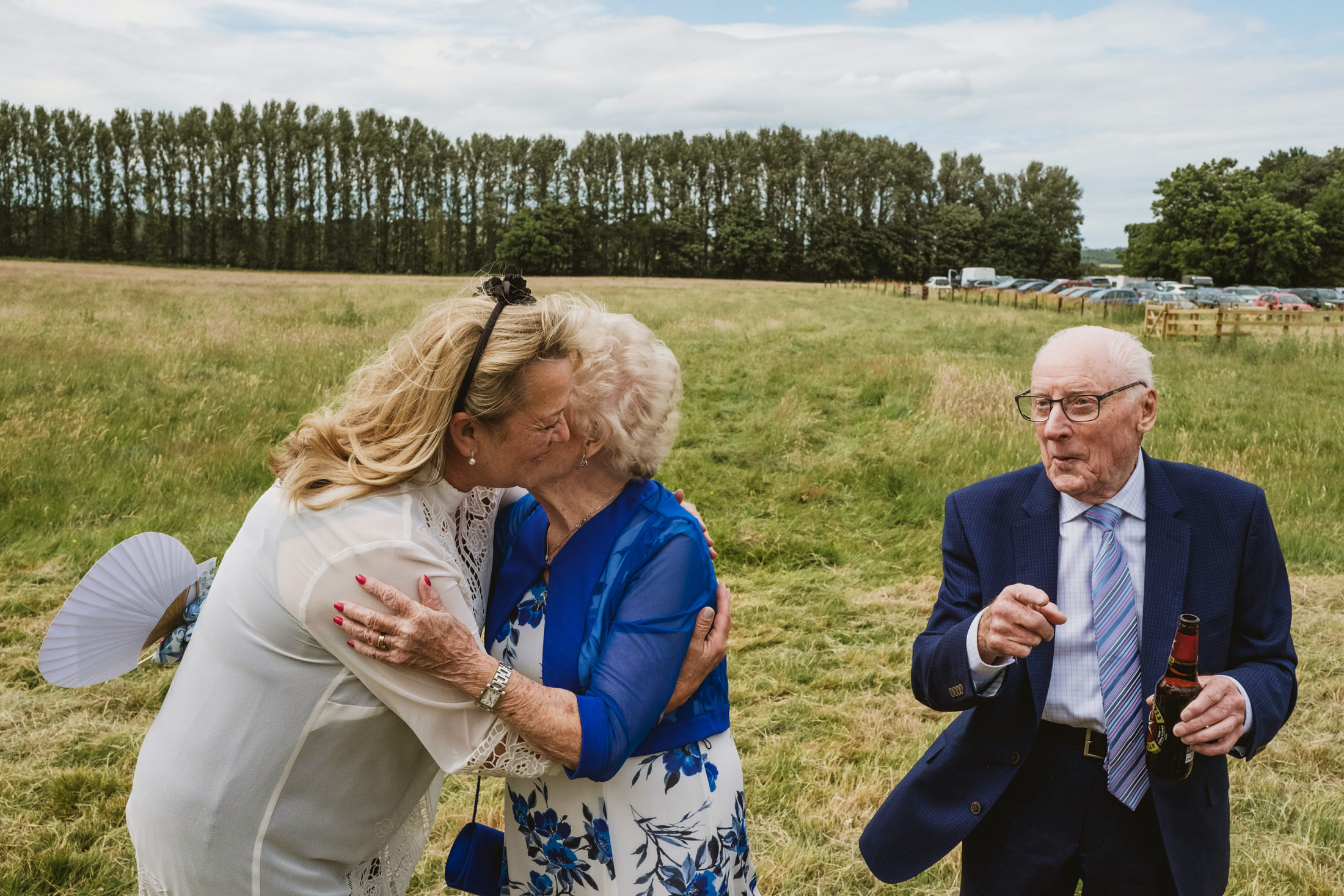 Three people in an outdoor gathering, embracing.