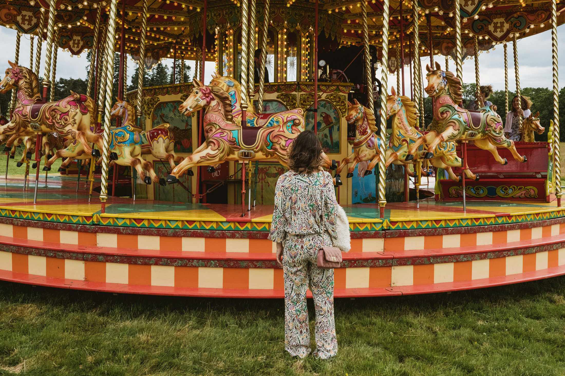 Woman admiring ornate vintage carousel with horses.