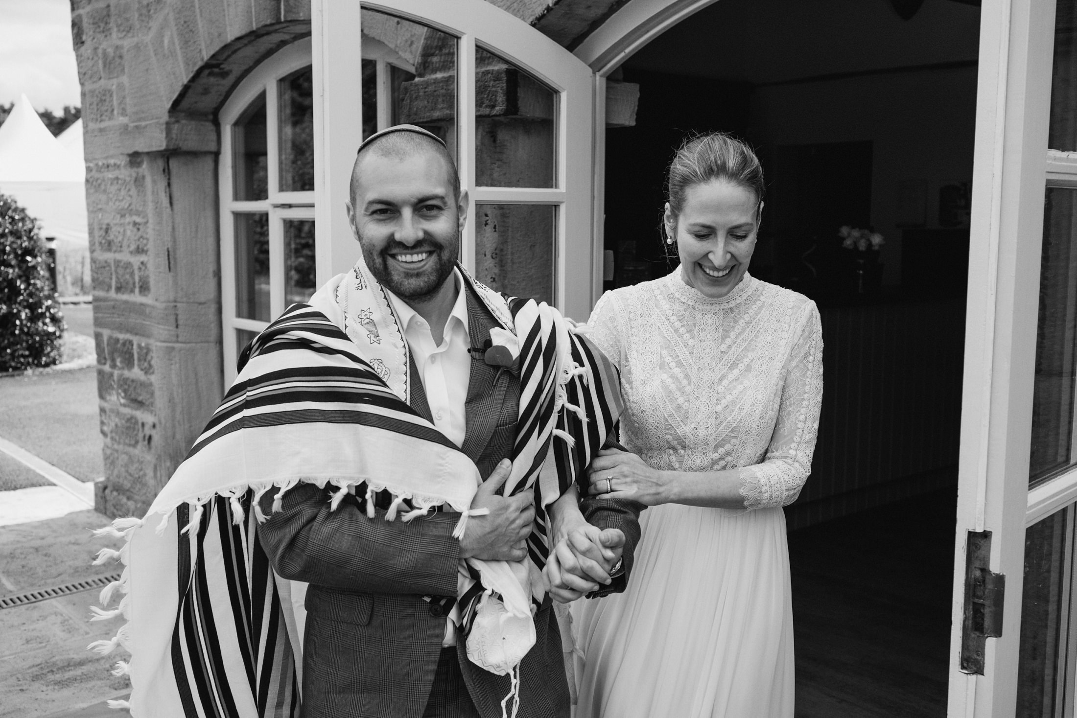 Smiling couple outside building on a wedding day.