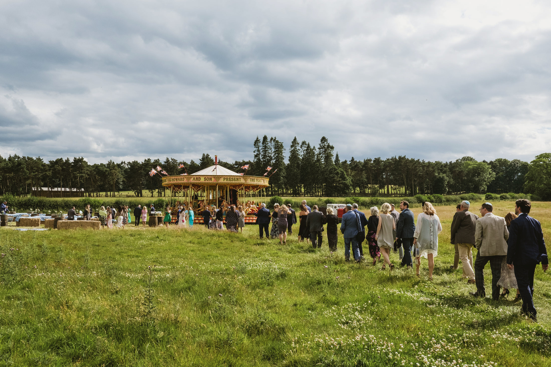 People walking towards outdoor vintage fairground carousel.