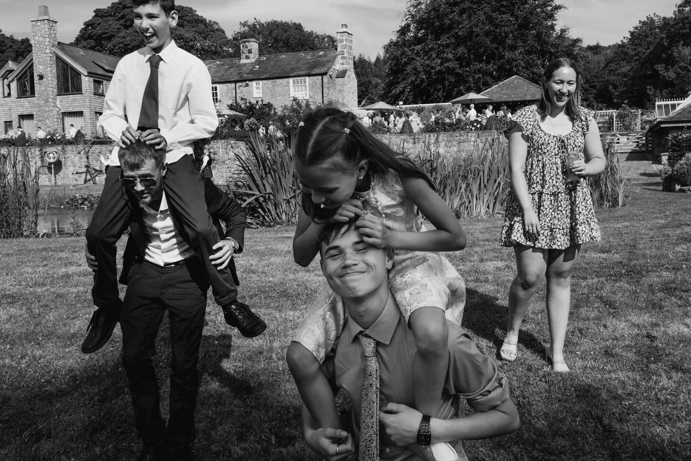 Children playing piggyback in garden, black and white photo.