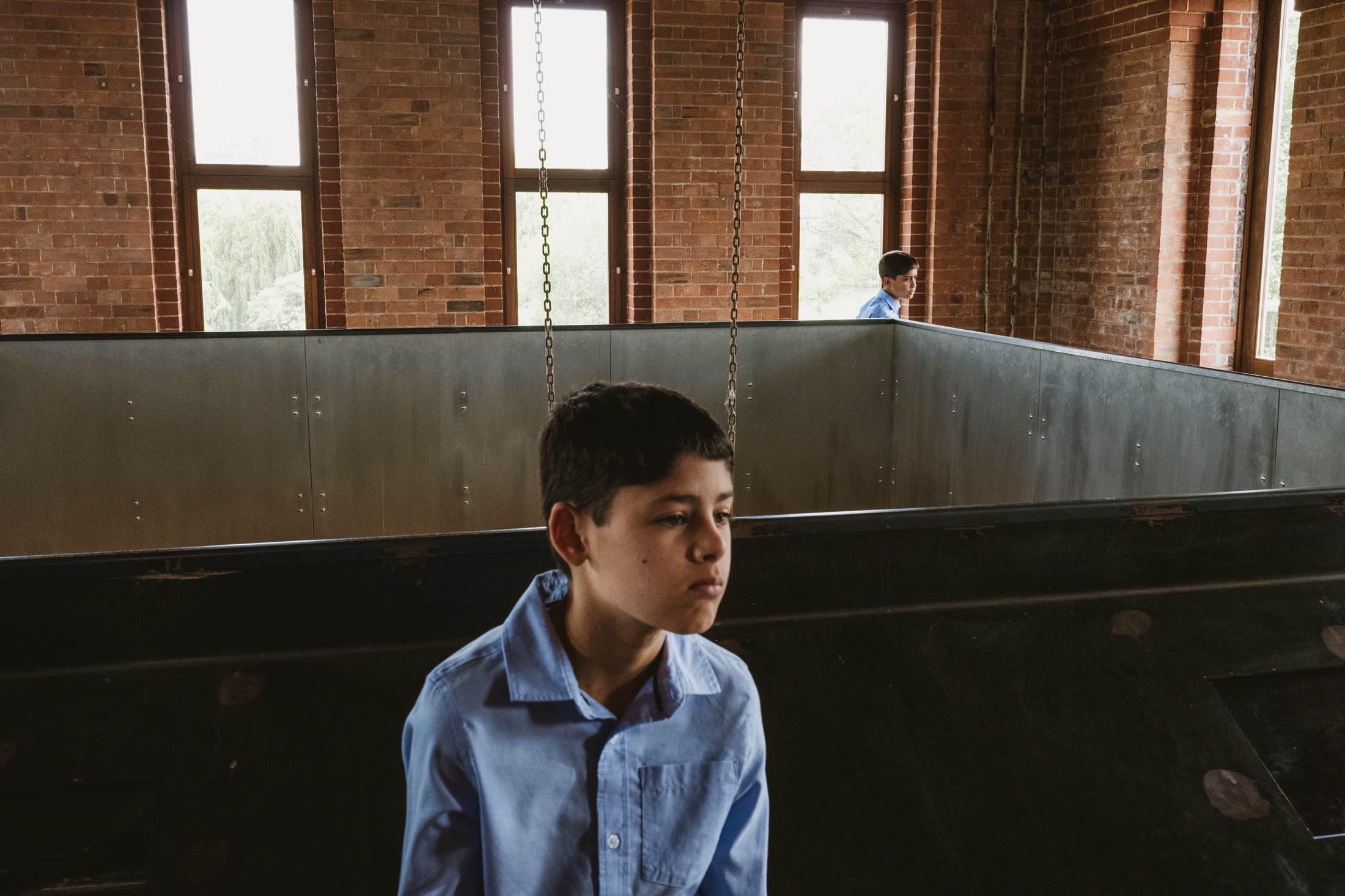 Boy in blue shirt inside brick building.