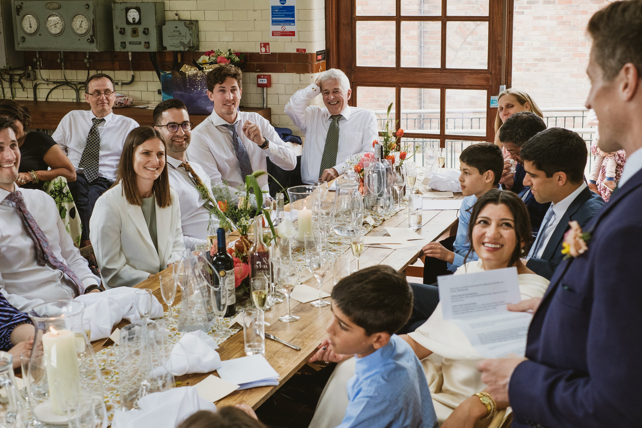 People smiling at a wedding reception speech.